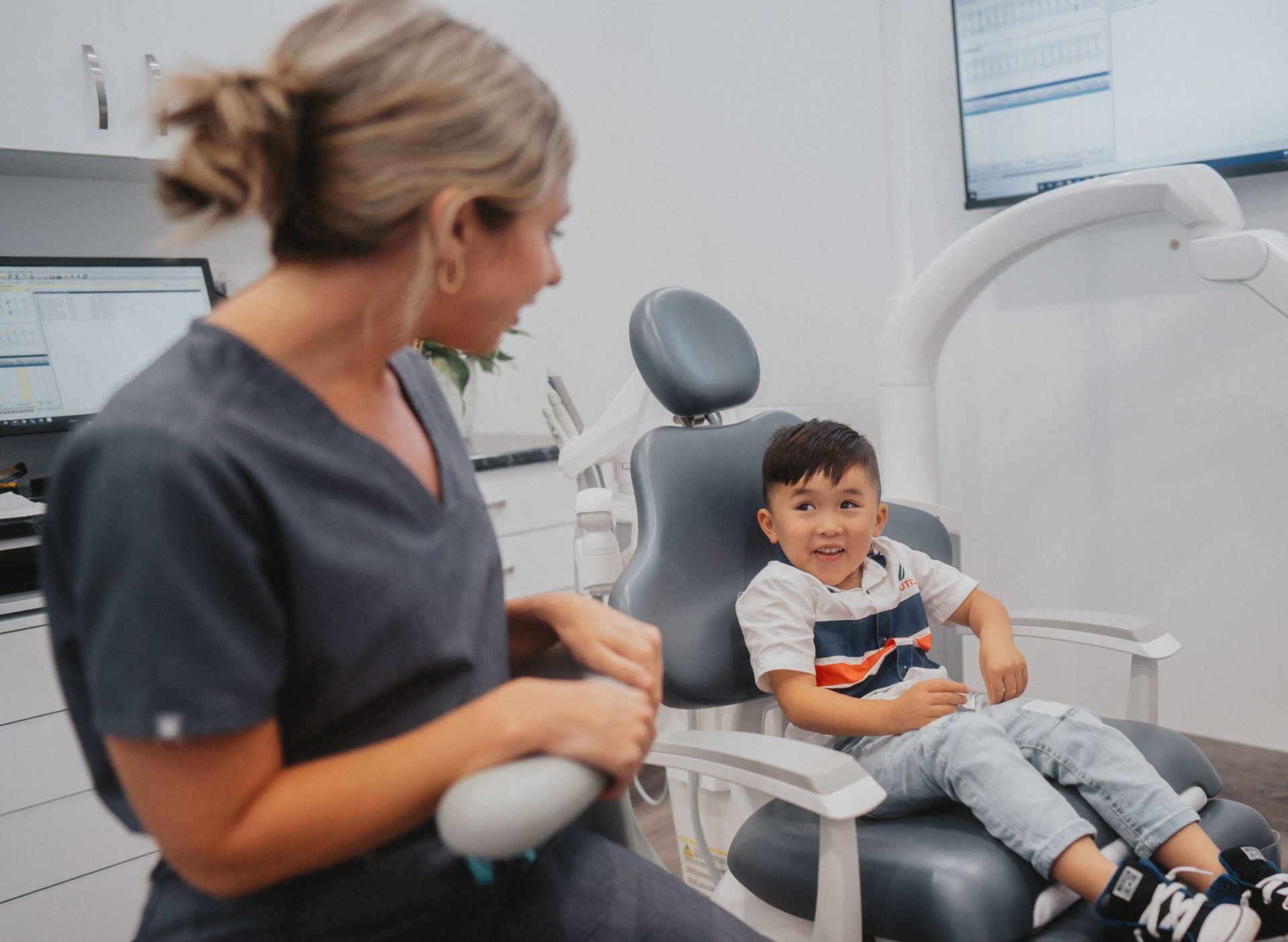 Young child smiling at a dental clinician during an appointment in a modern dental surgery.