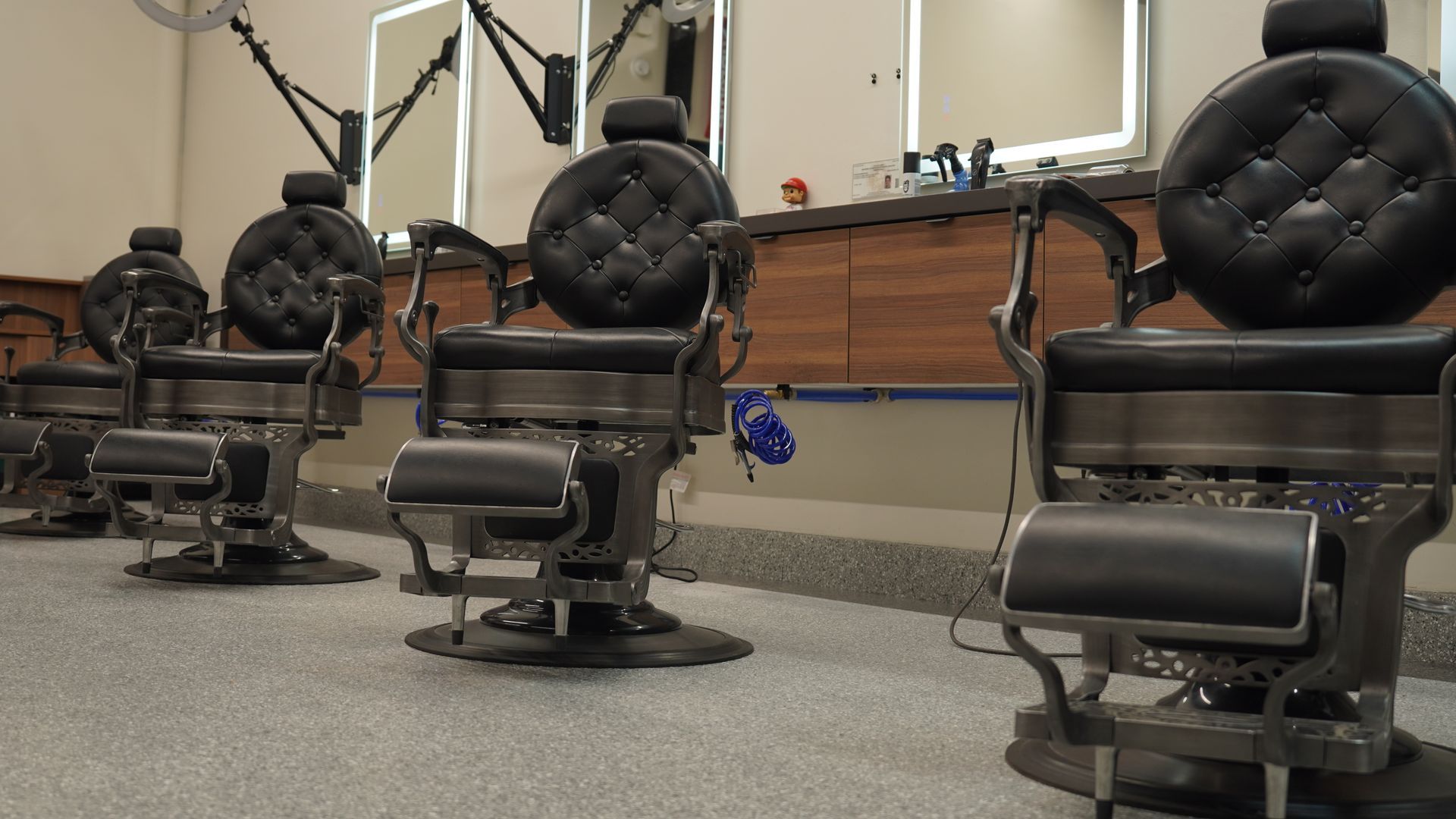 Barber chairs in a salon, dark leather seats, metal frames, mirrors in the background.