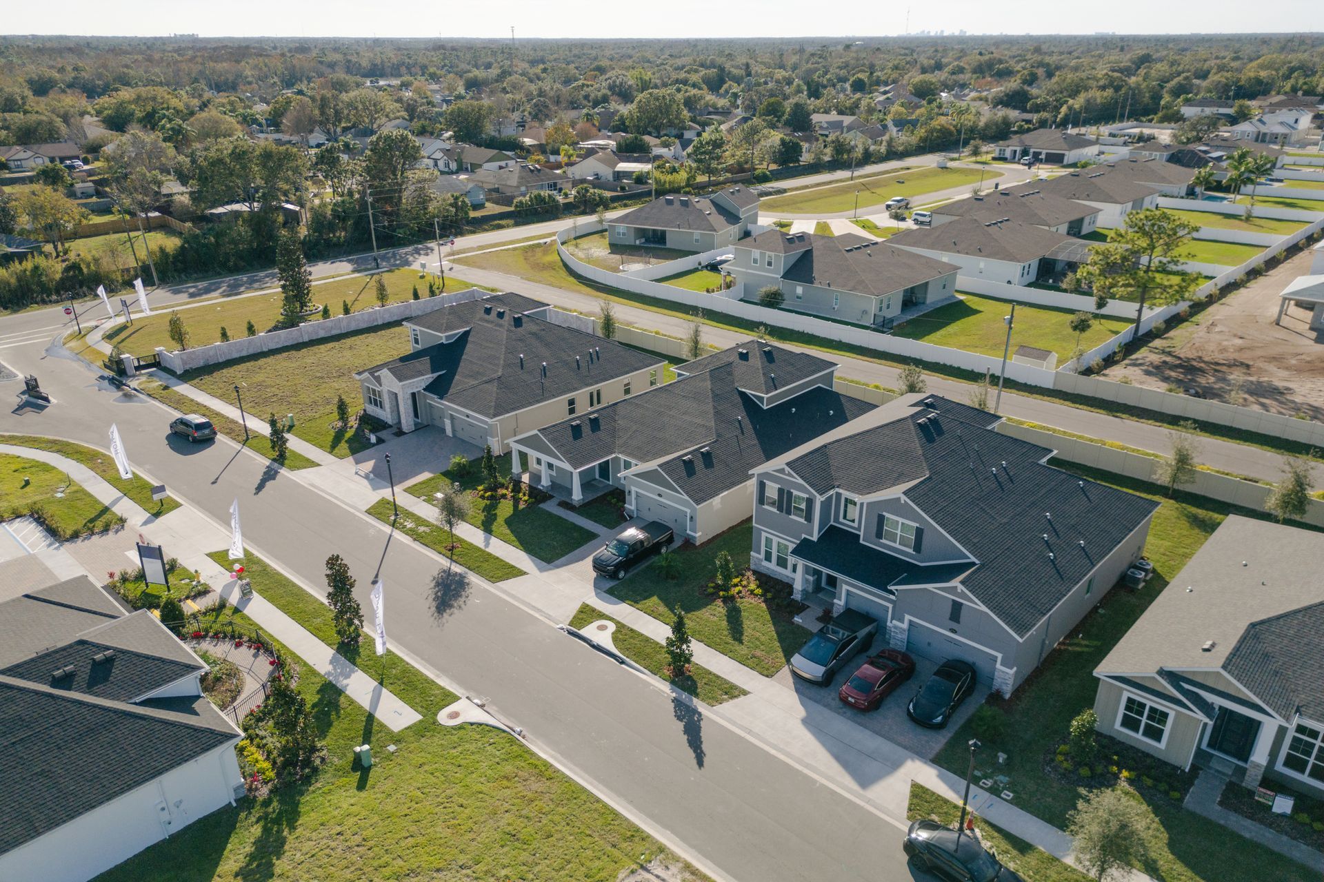 Aerial view of a residential neighborhood with new houses, roads, and trees on a sunny day.