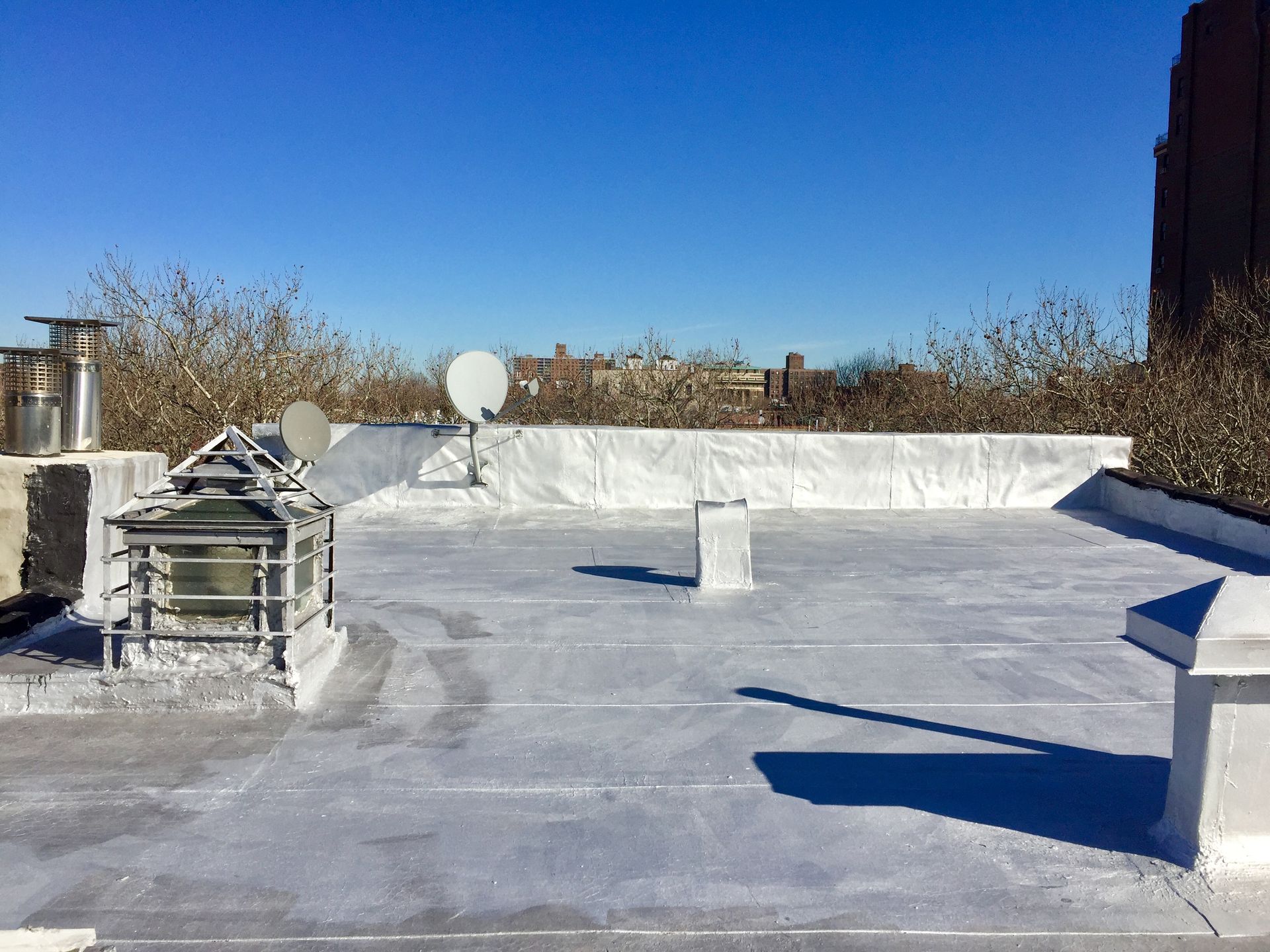 Rooftop view on a sunny day with various structures, including satellite dish, and a clear blue sky.