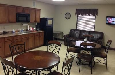 Community room with kitchen, round tables, chairs, couch, and TV against the wall.