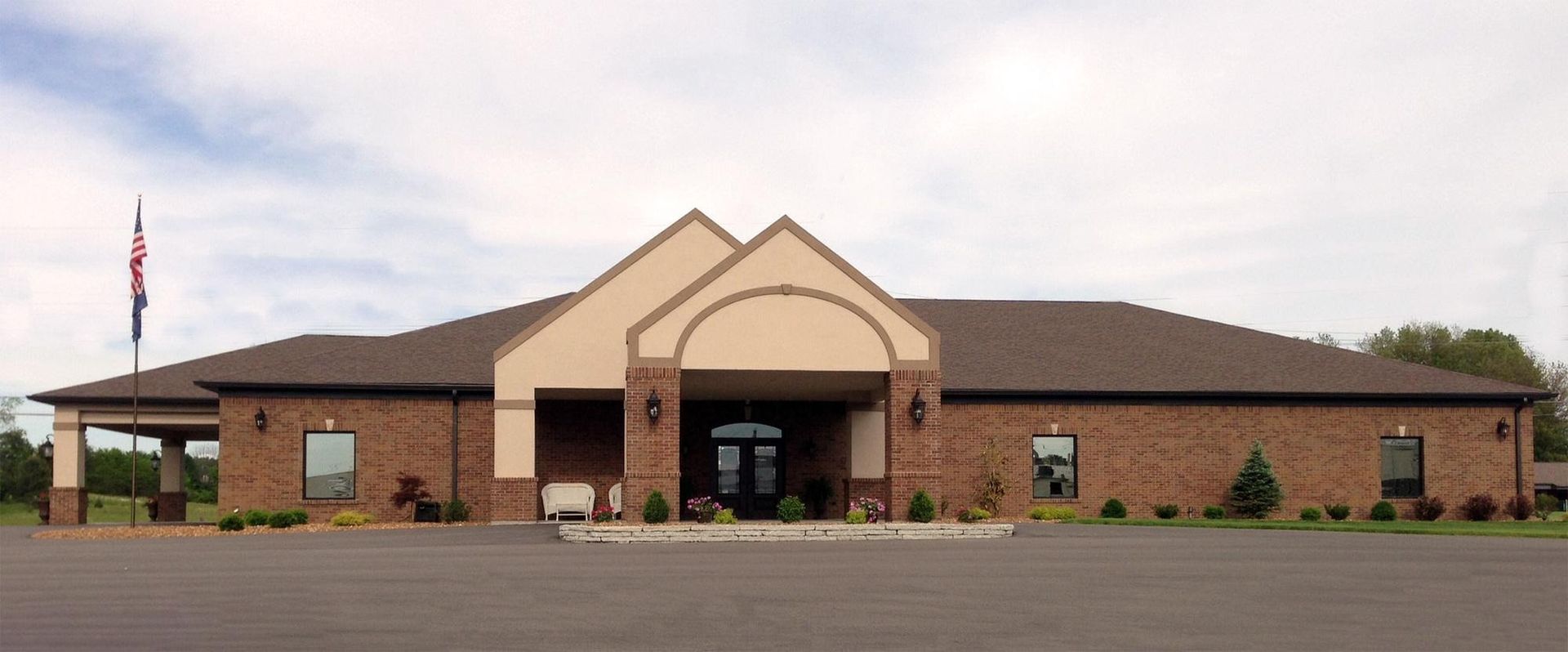 Front view of a brick community building with a central entrance and an American flag outside