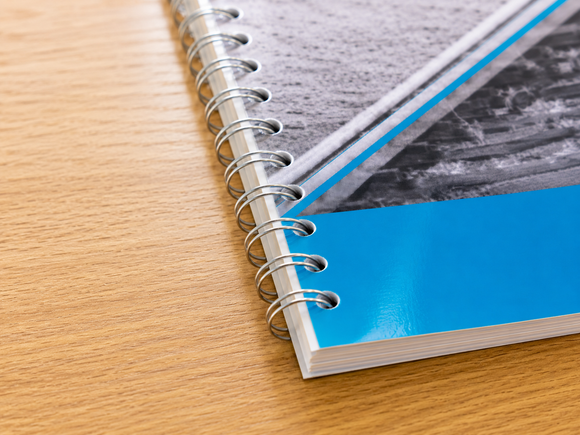 Spiraalgebonden notitieboek met blauwe kaft op een houten bureau, close-up