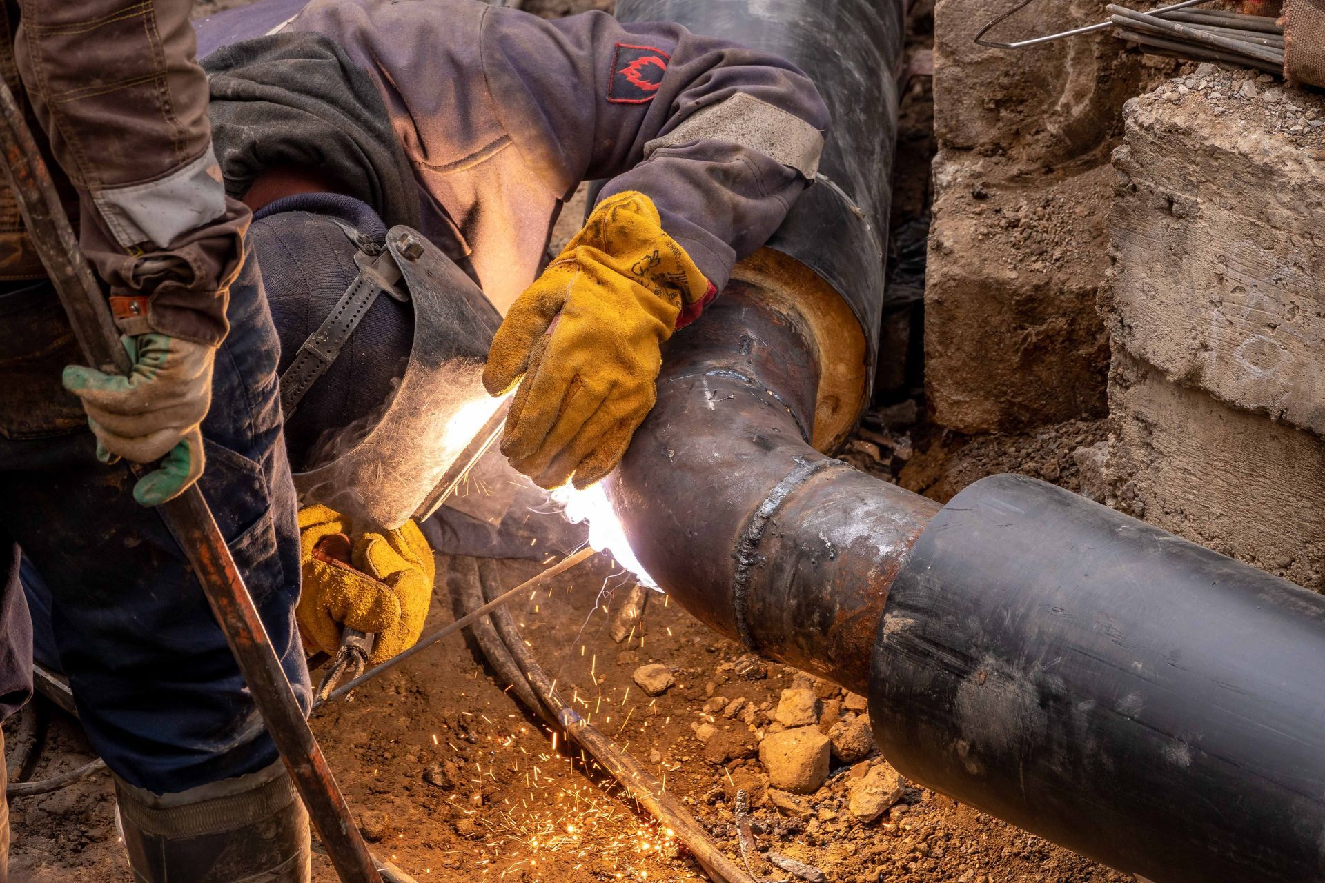 Worker welding steel pipes in an industrial setting