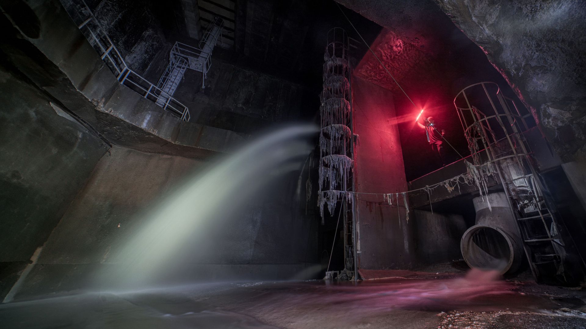 Person standing inside a long underground tunnel with dramatic light