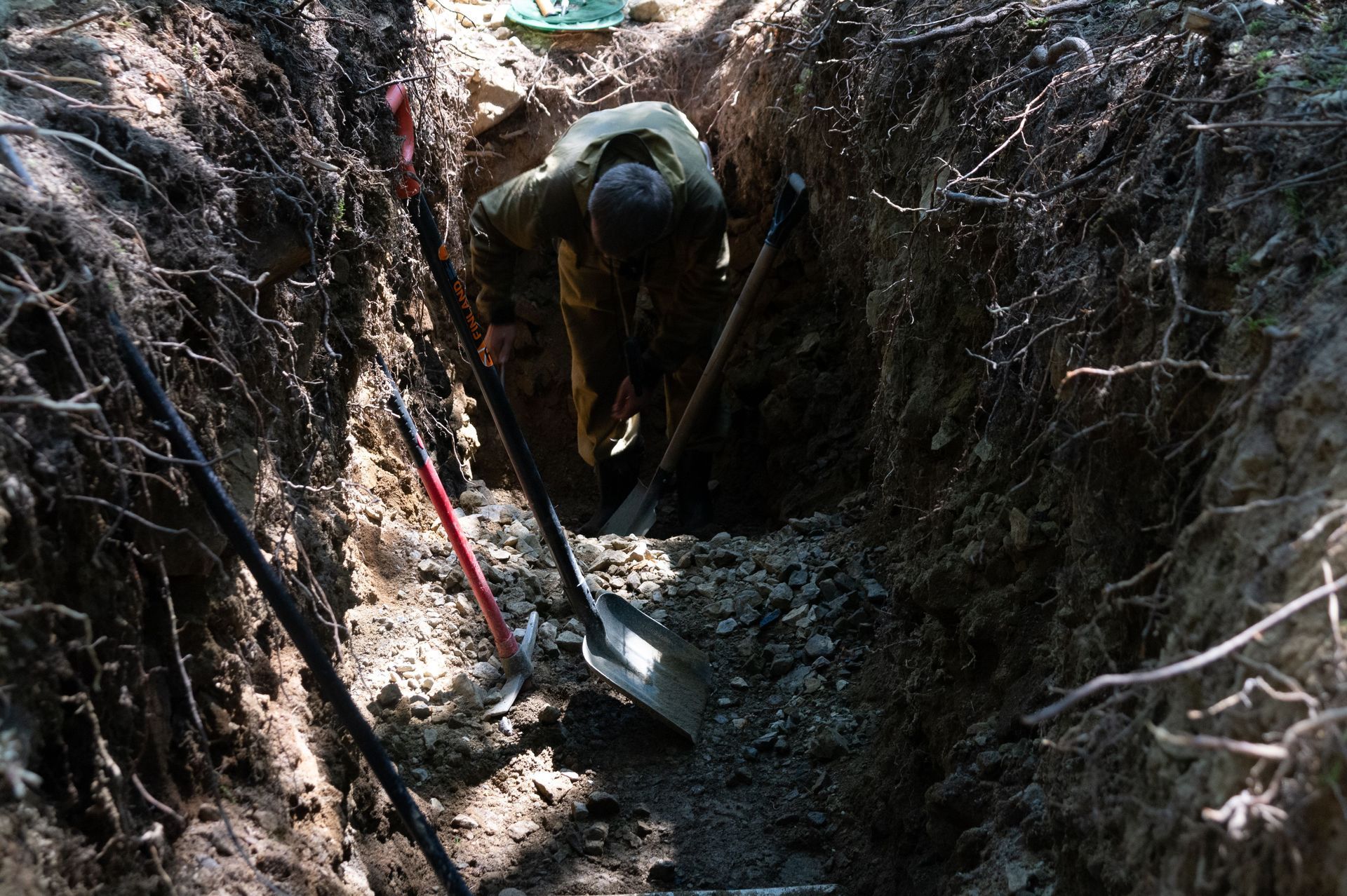 Person digging a trench by hand at a construction site