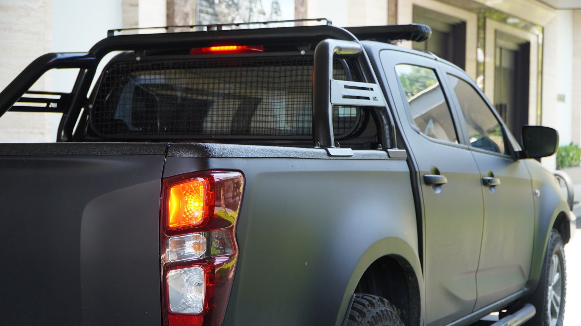 Rear view modern matte black double-cab pickup truck with customized off-road accessories.