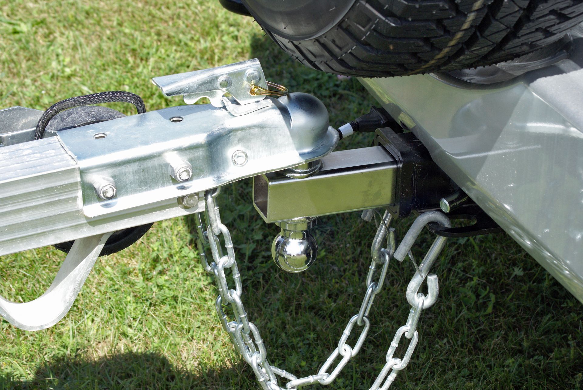 Close-up of trailer hitch with coupling, safety chains, and tow ball attached.