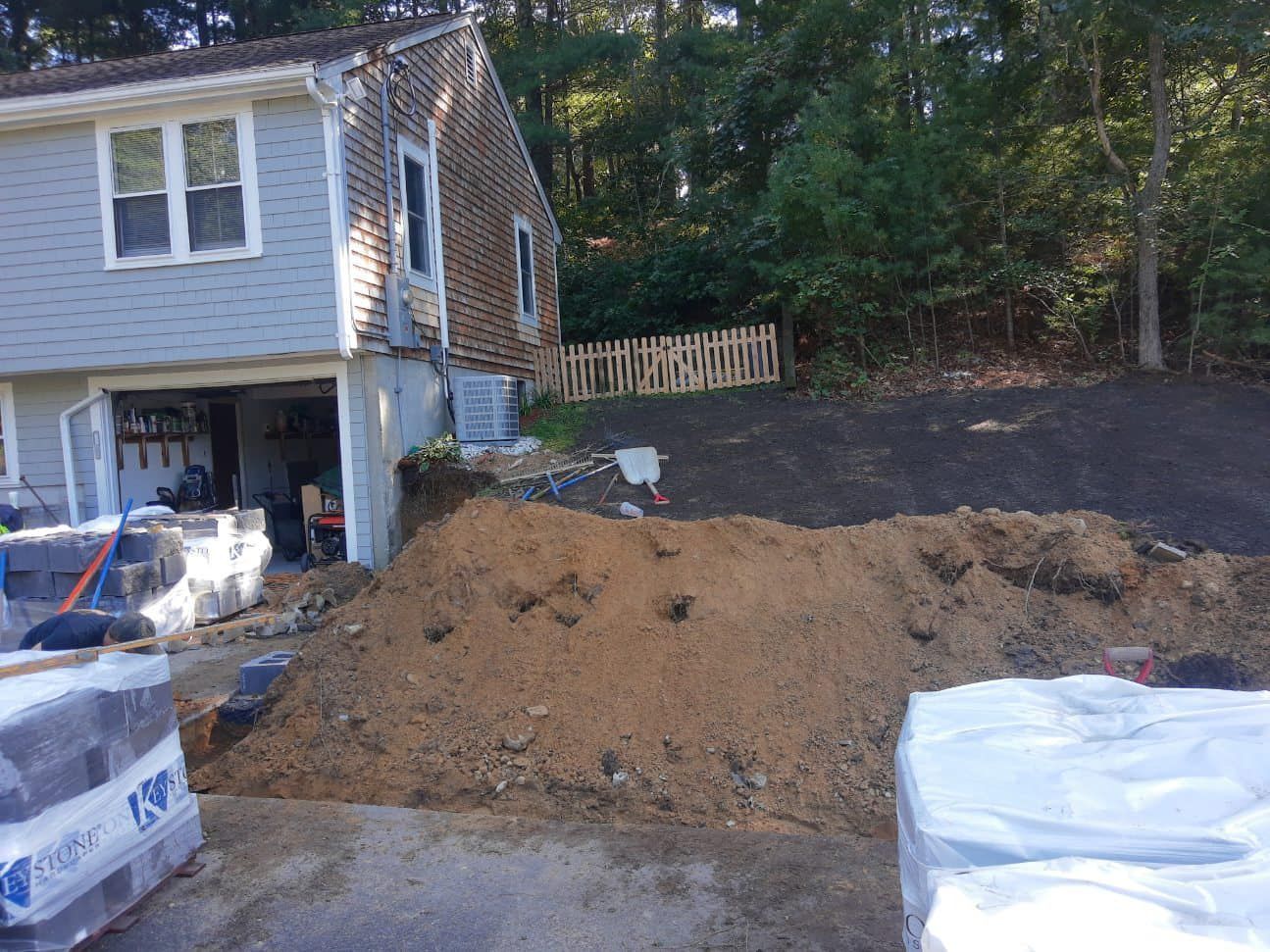 Construction site with a house, a pile of dirt, and building materials.