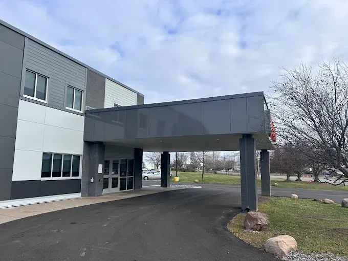 Building entrance with covered drive-through canopy and parking area on a cloudy day