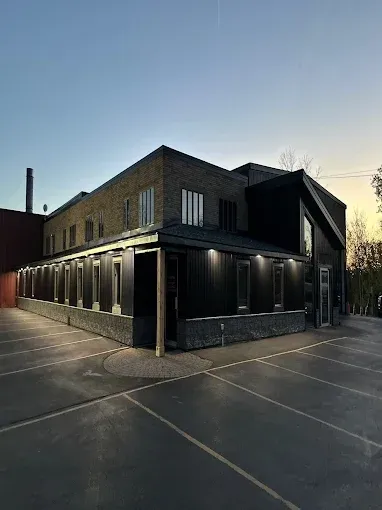 Modern brick building at dusk with illuminated exterior columns and empty paved lot