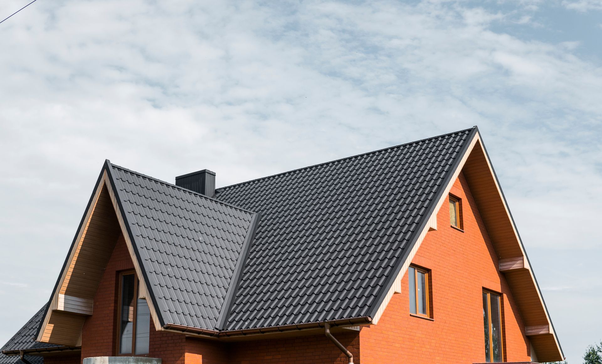 Orange house with dark gray gabled roof under a cloudy sky