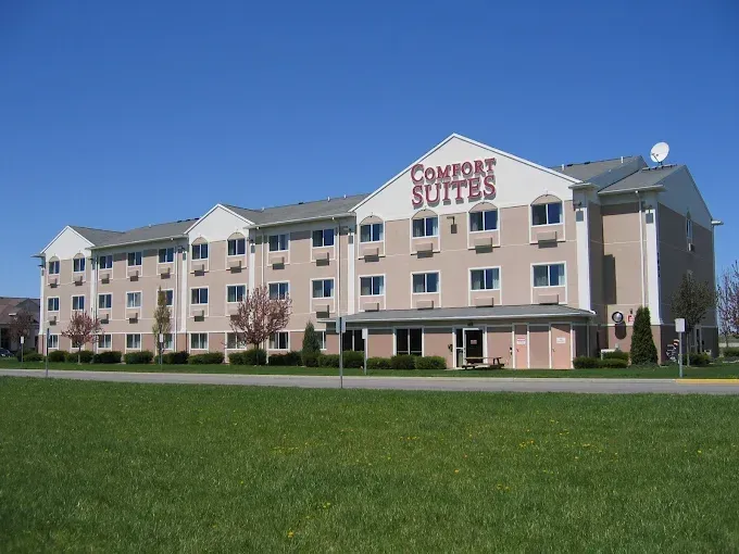 Comfort Suites hotel exterior with beige facade and green lawn under a clear blue sky