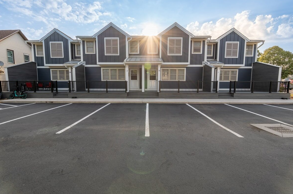 Empty parking lot in front of a row of gray townhouses at sunset