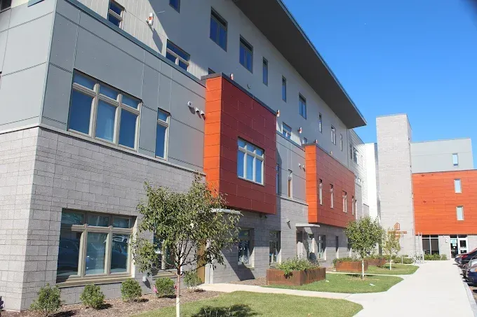 Modern apartment building with gray and orange facades and a landscaped walkway