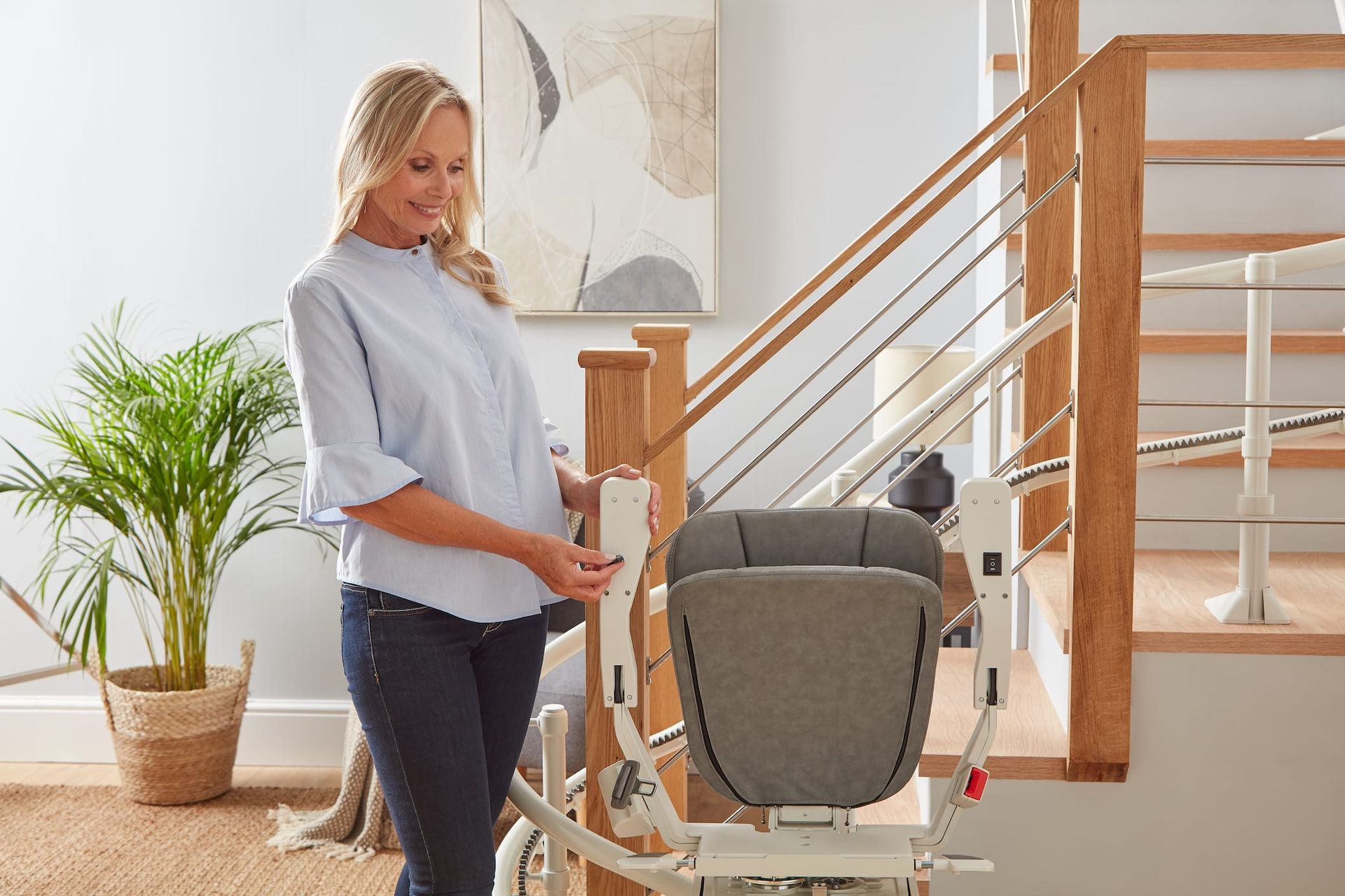 Woman using a stair lift beside a staircase in a bright home interior