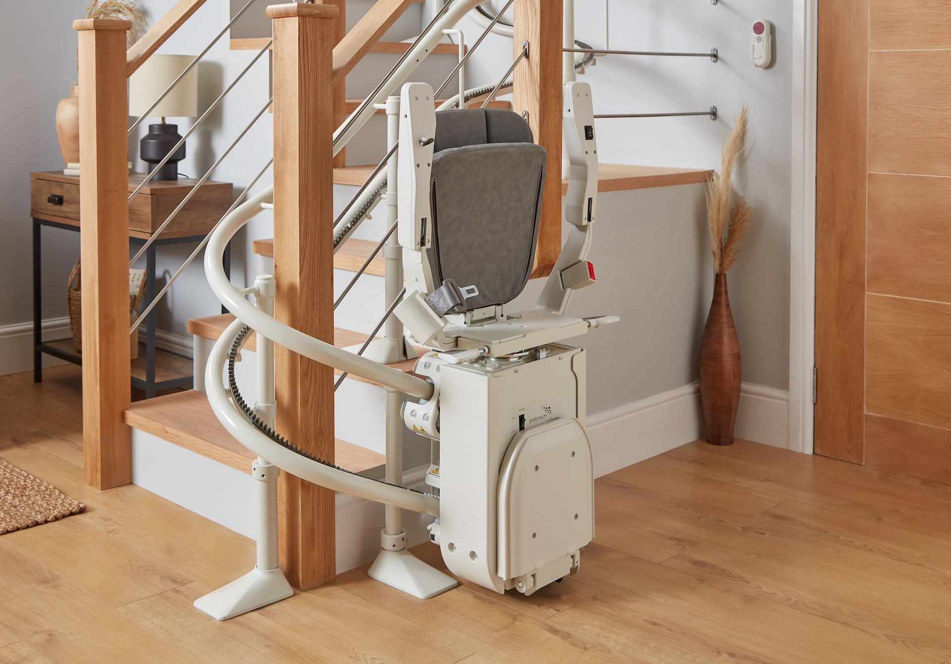 Stairlift on a wooden staircase in a home interior, with a curved rail and folded seat.