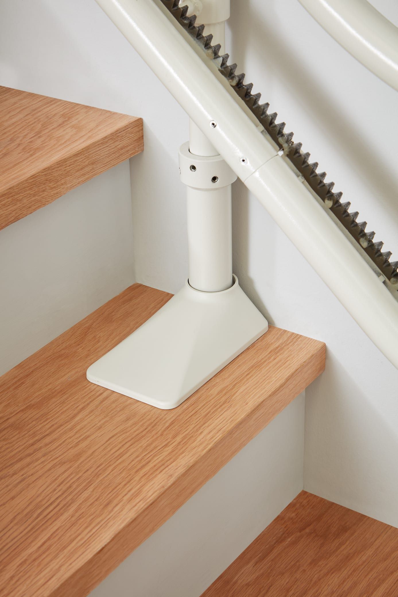 White stair handrail support mounted on carpeted stairs near a wooden banister