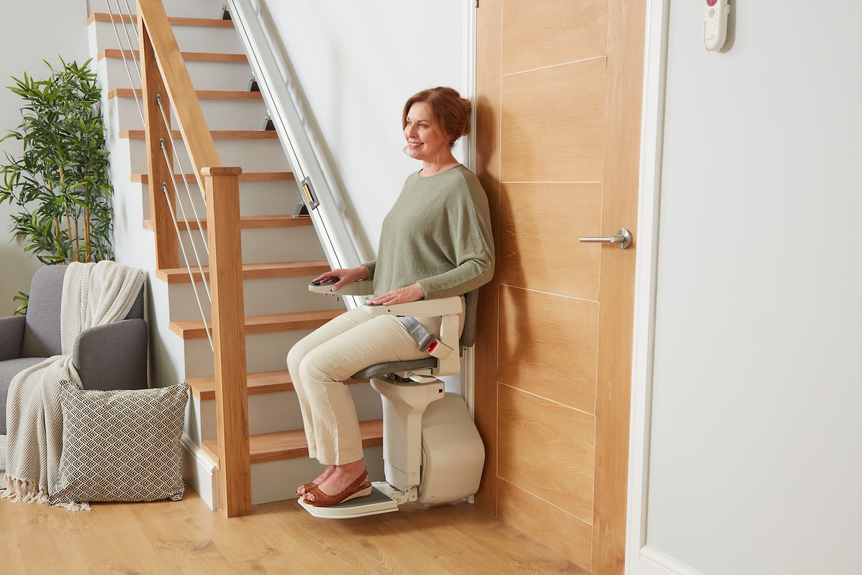 Woman using a stairlift beside a wooden staircase in a bright home interior