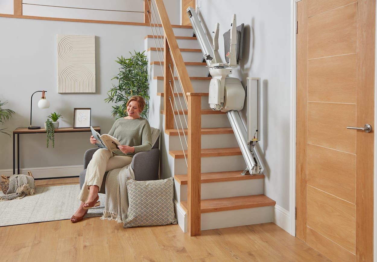 Woman relaxing in a chair in a bright living room beside a staircase lift and staircase