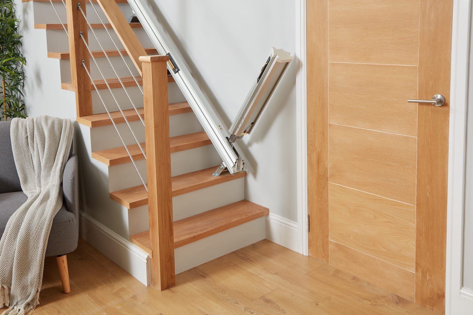 Wooden staircase with a stairlift beside a closed wooden door in a home interior