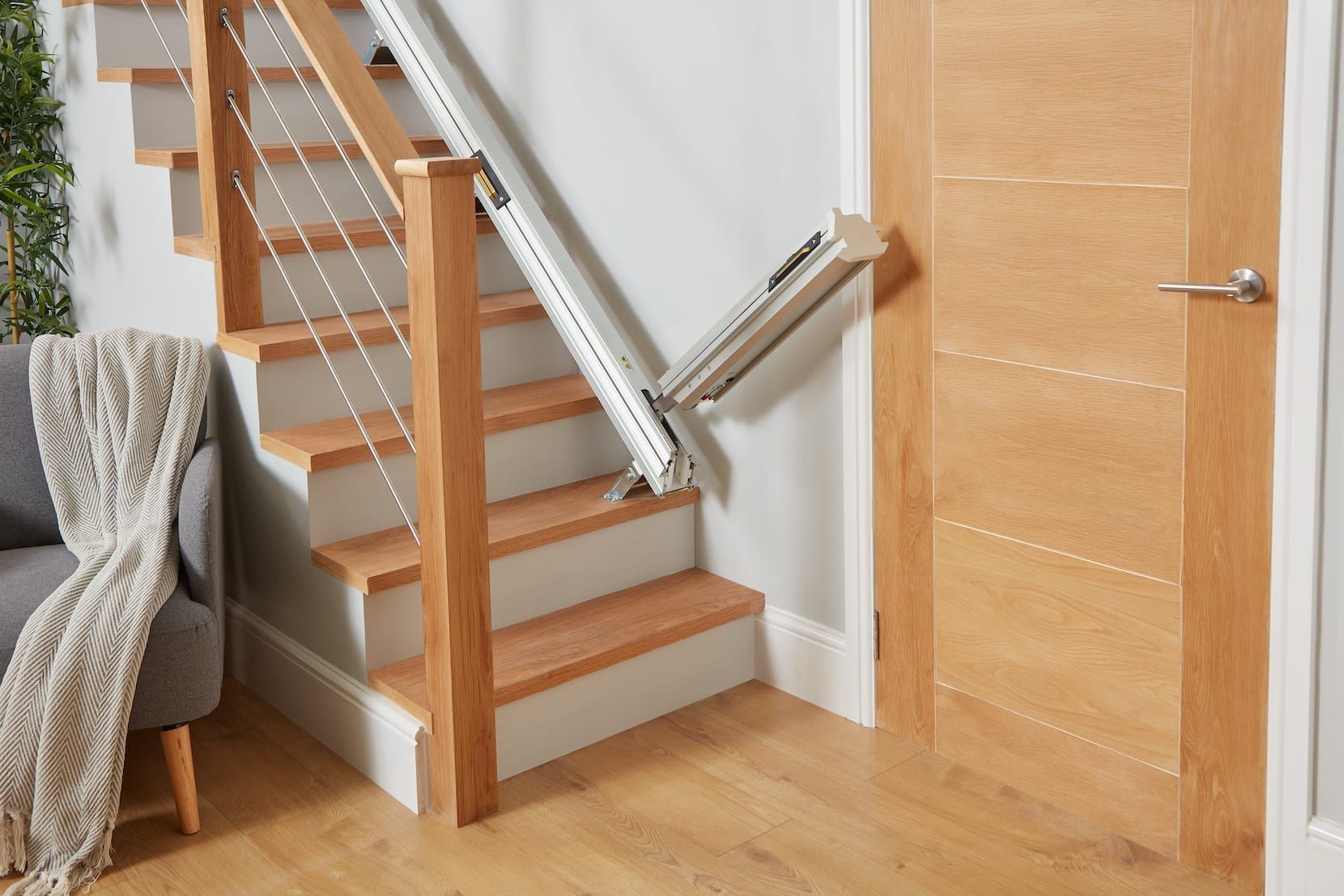 Indoor staircase with wood steps and metal railing beside a wooden door and chair