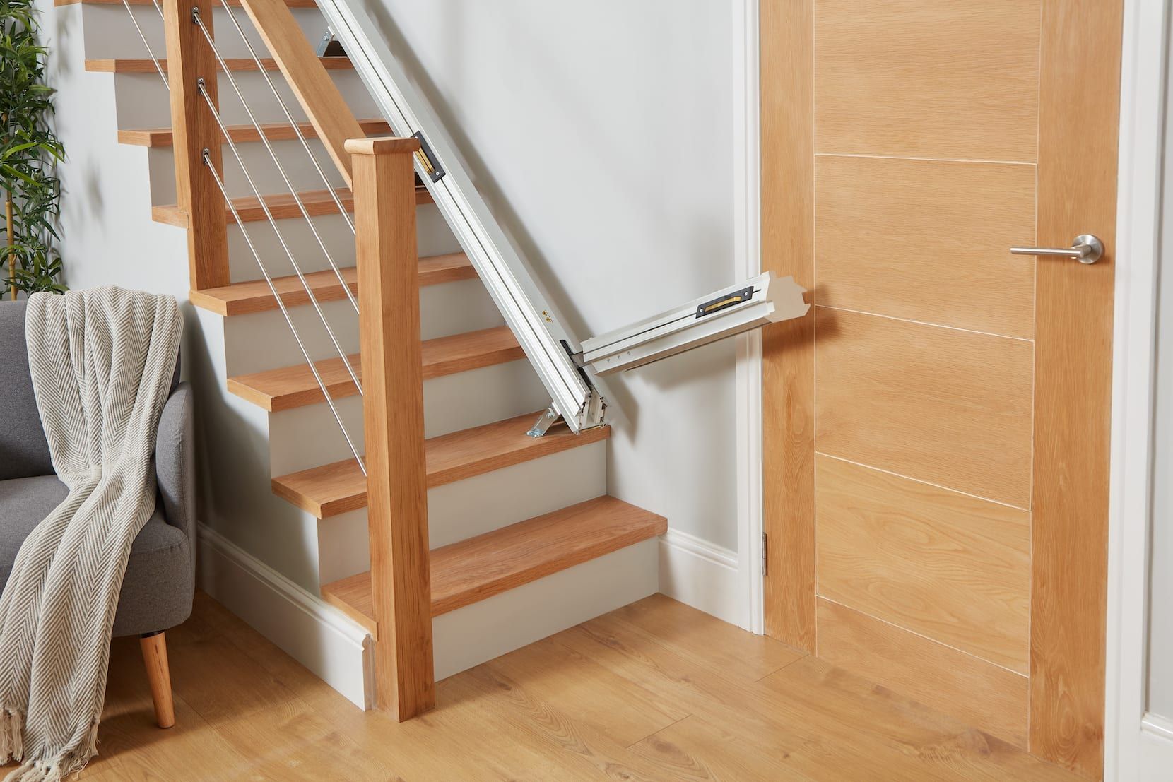 Interior staircase with a chairlift beside wooden stairs and a closed door nearby