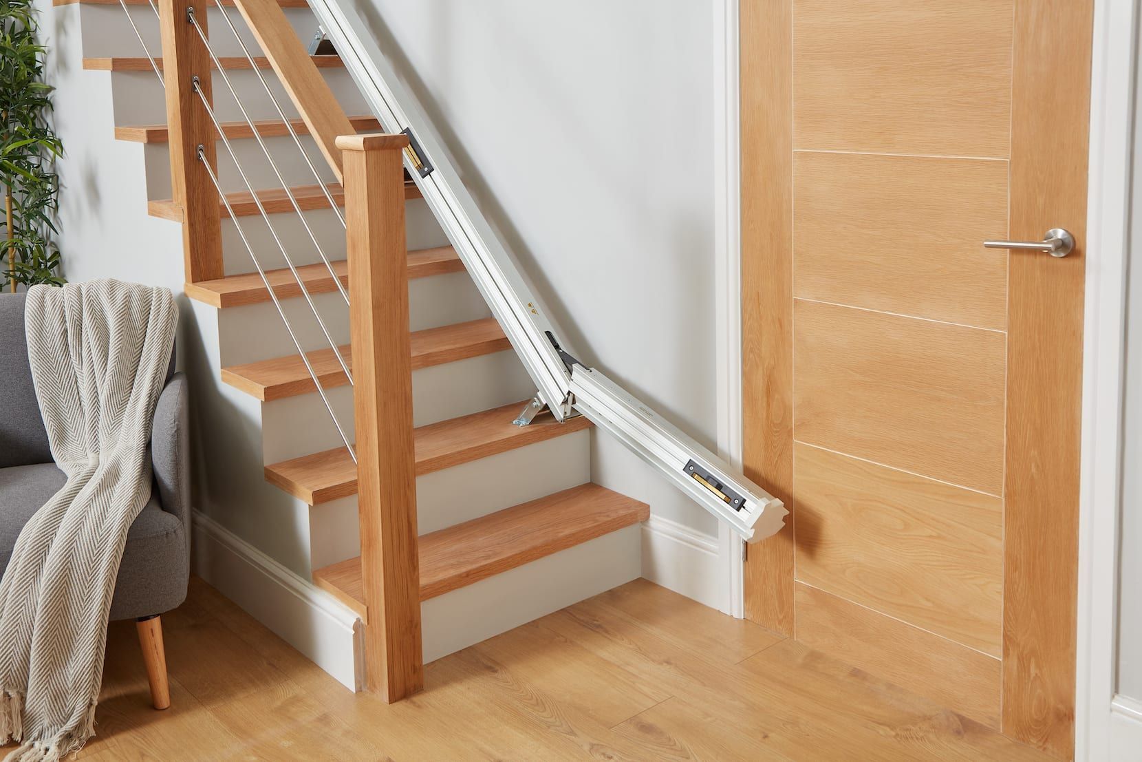 Indoor staircase with white handrails, wooden steps, and a closed wooden door beside it