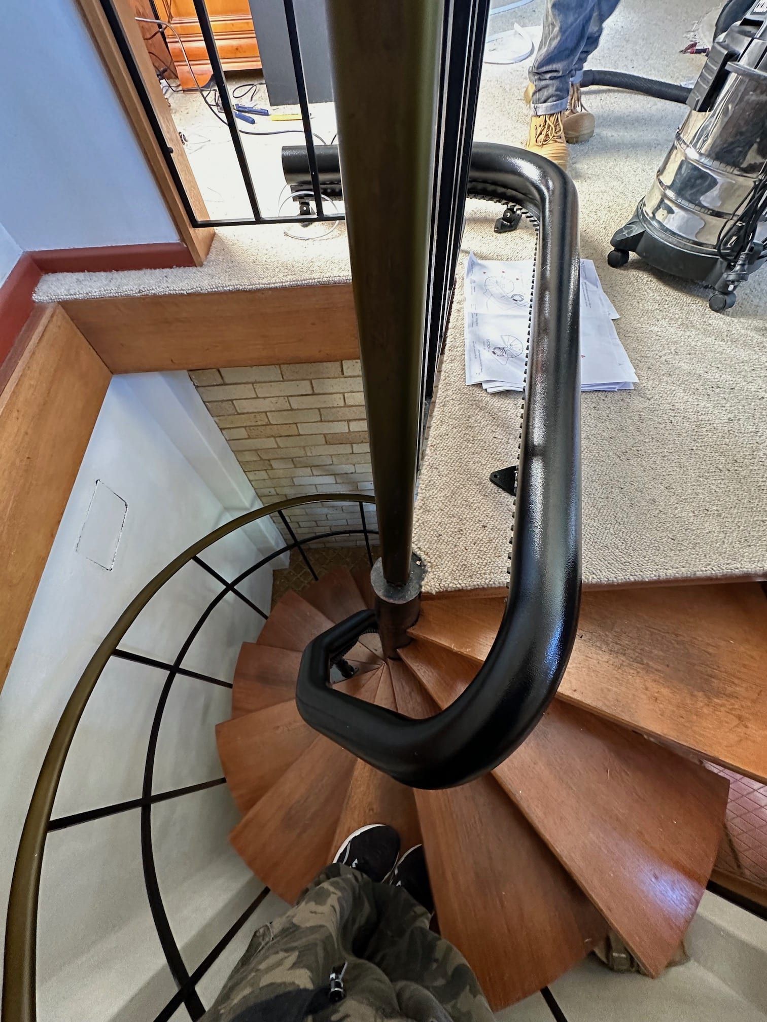 Spiral wooden staircase with black metal handrail in a home interior