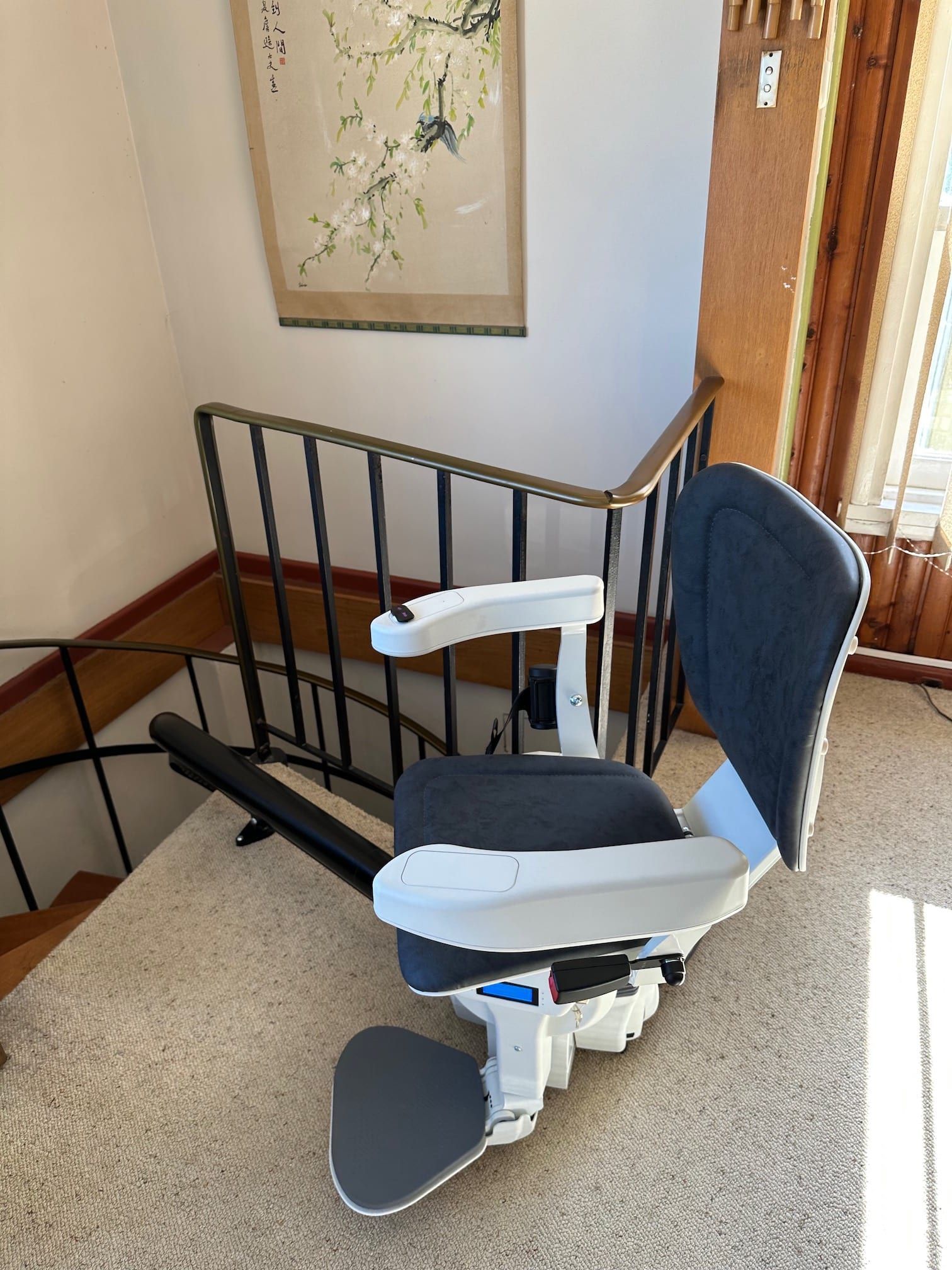 Portable stairlift beside a carpeted staircase in a home hallway