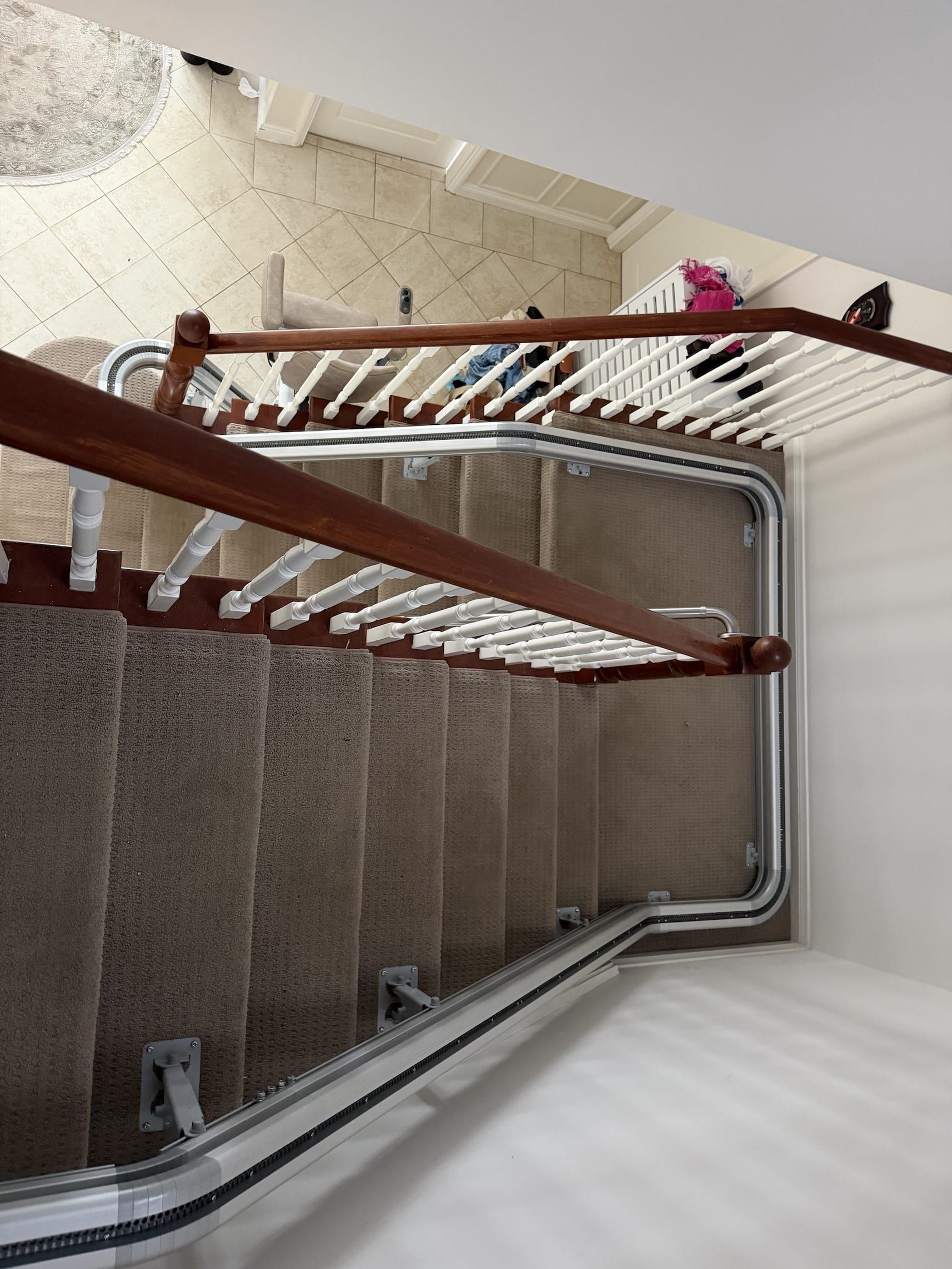 Top-down view of a stairwell with carpeted steps, metal railings, and white walls.