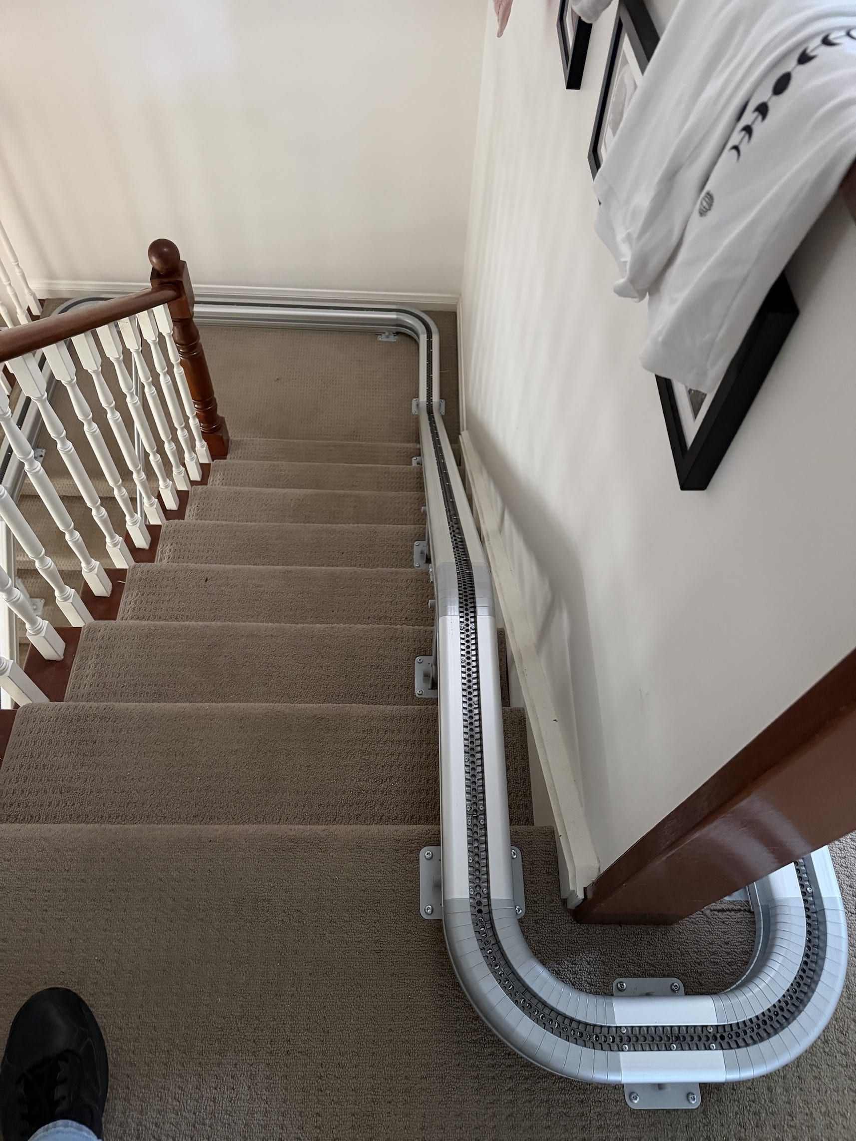 Staircase with carpeted steps and white handrails descending to a corner landing indoors