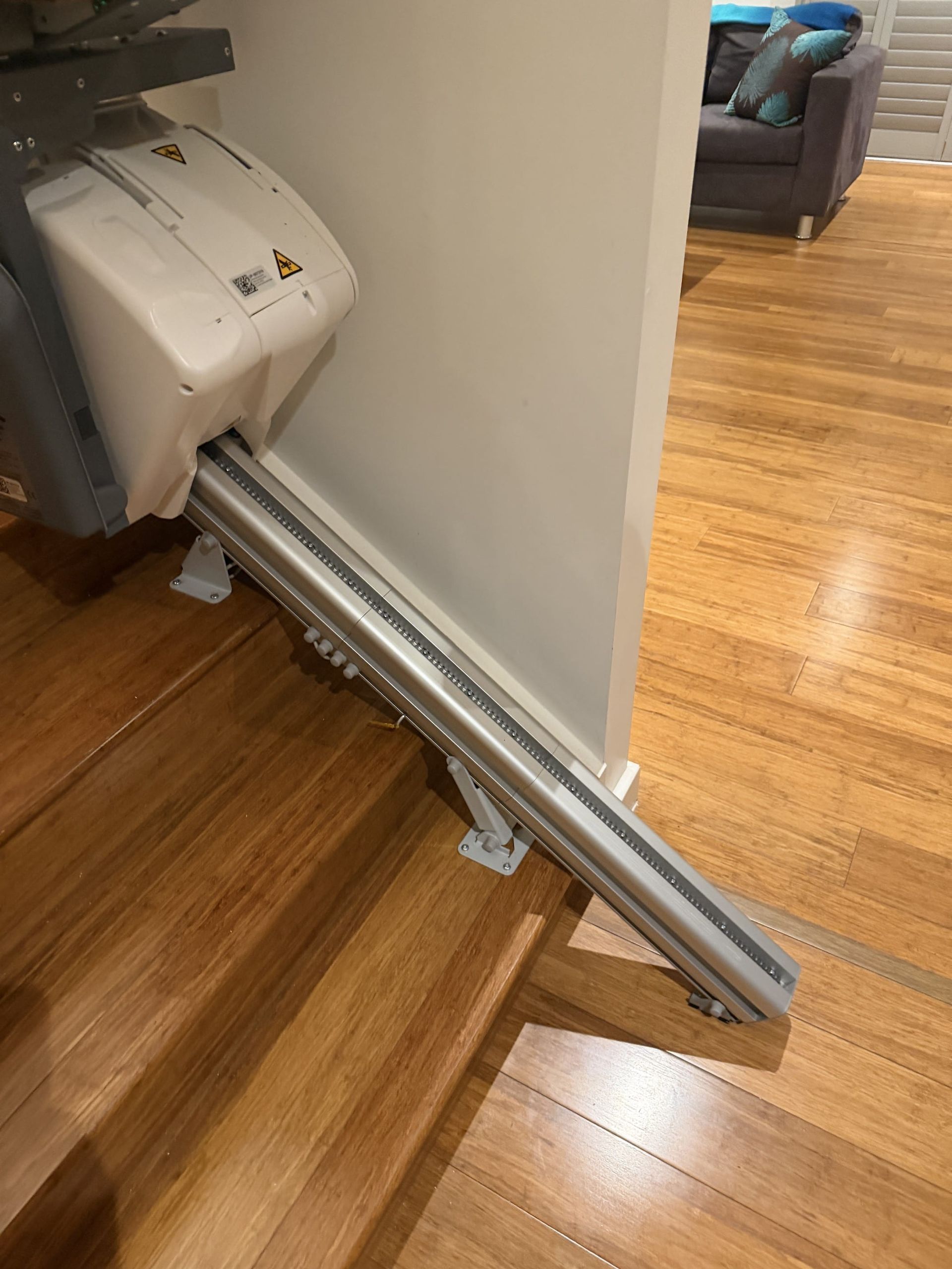 Broken folding treadmill leaning against a wall on a hardwood floor in a home.