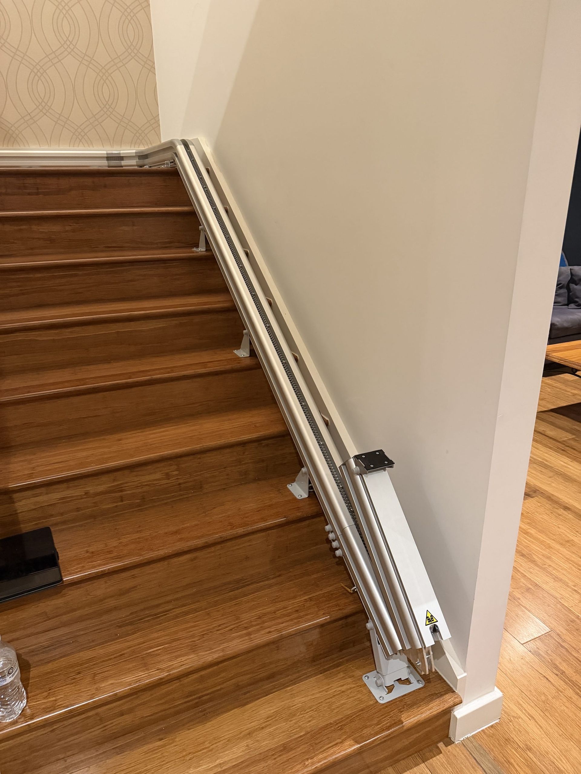 Stairwell with wooden steps and a long metal rail or track along the right wall.