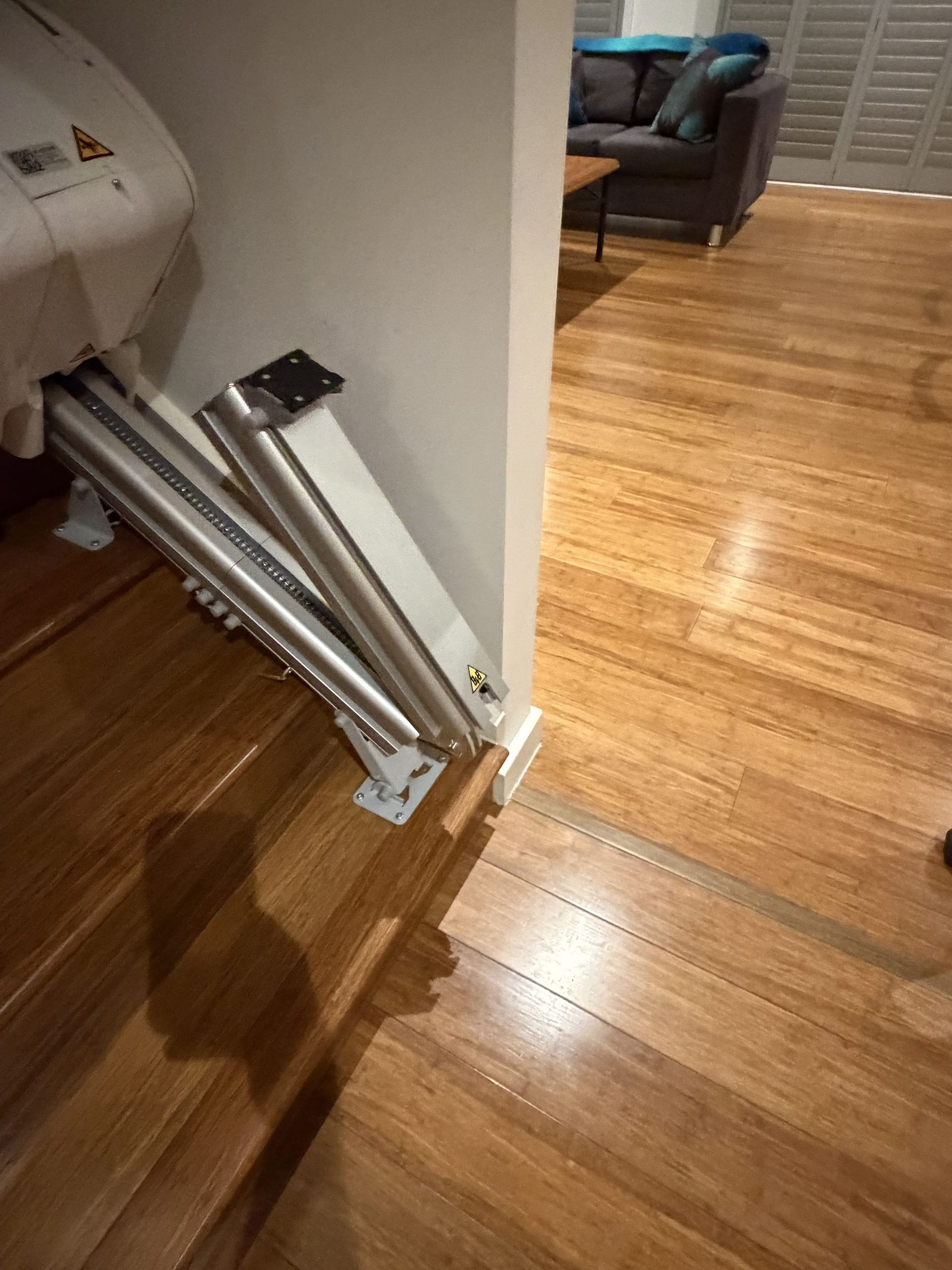 Folded silver walker leaning against a wall on a hardwood floor in a living room.