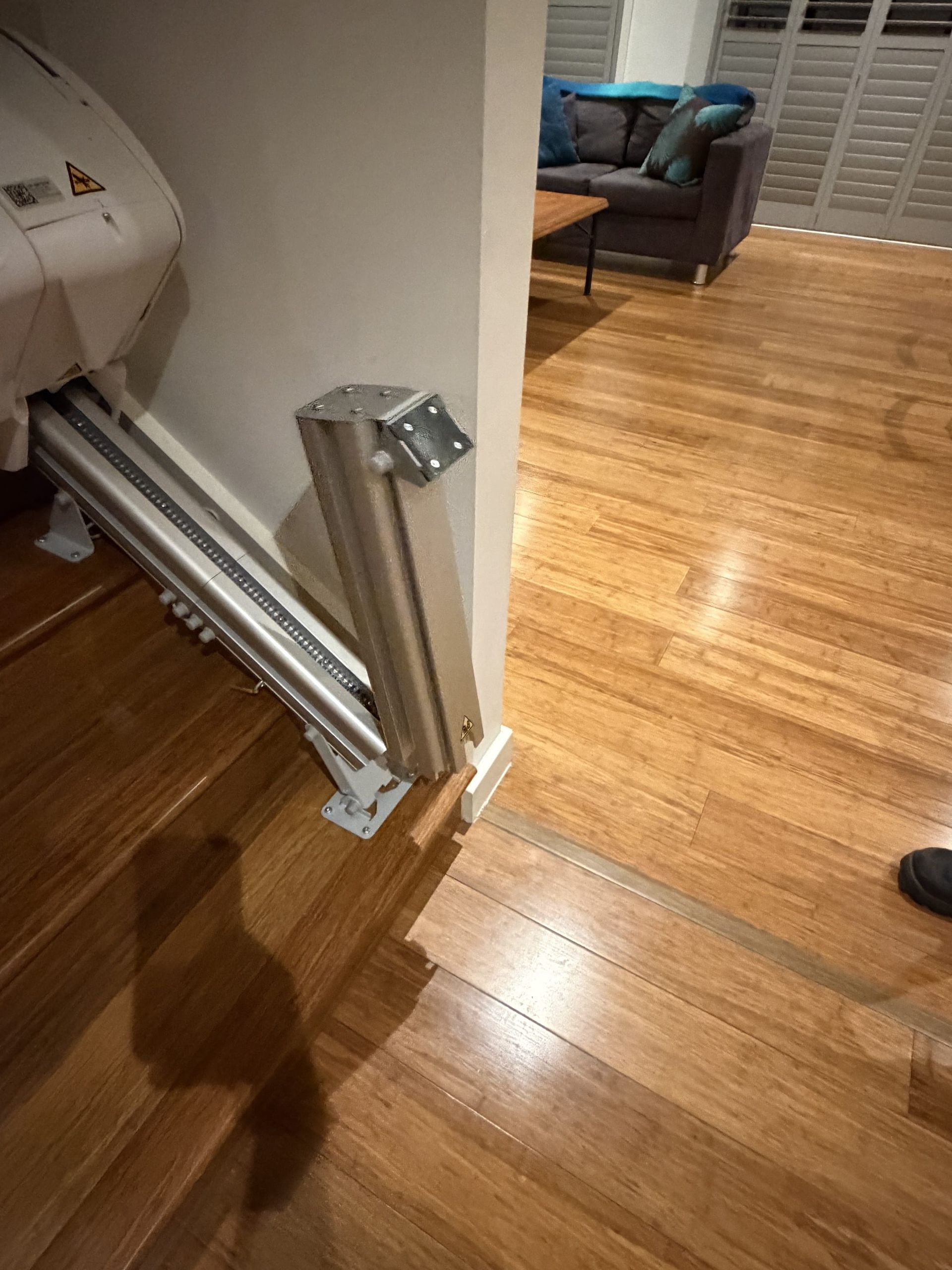Partially open folding gate blocking a doorway, with hardwood floors and a chair in the background