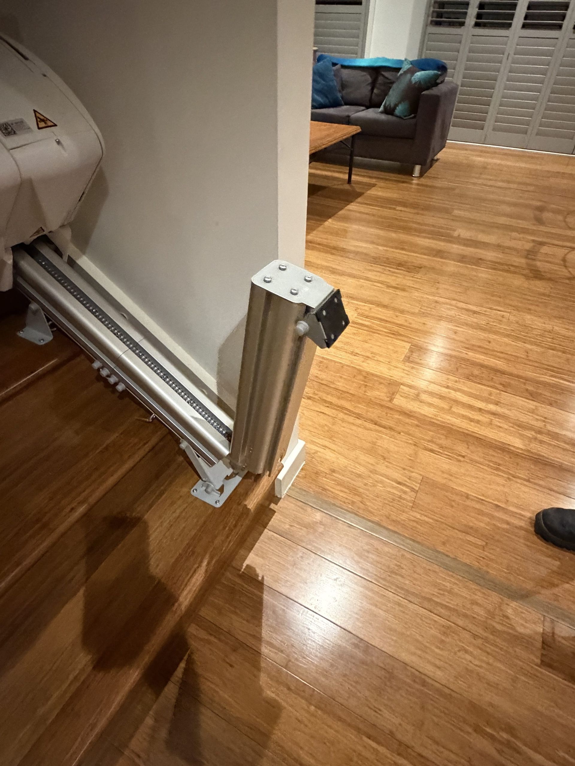 Folded metal doorway ramp beside a wooden floor in a home interior.