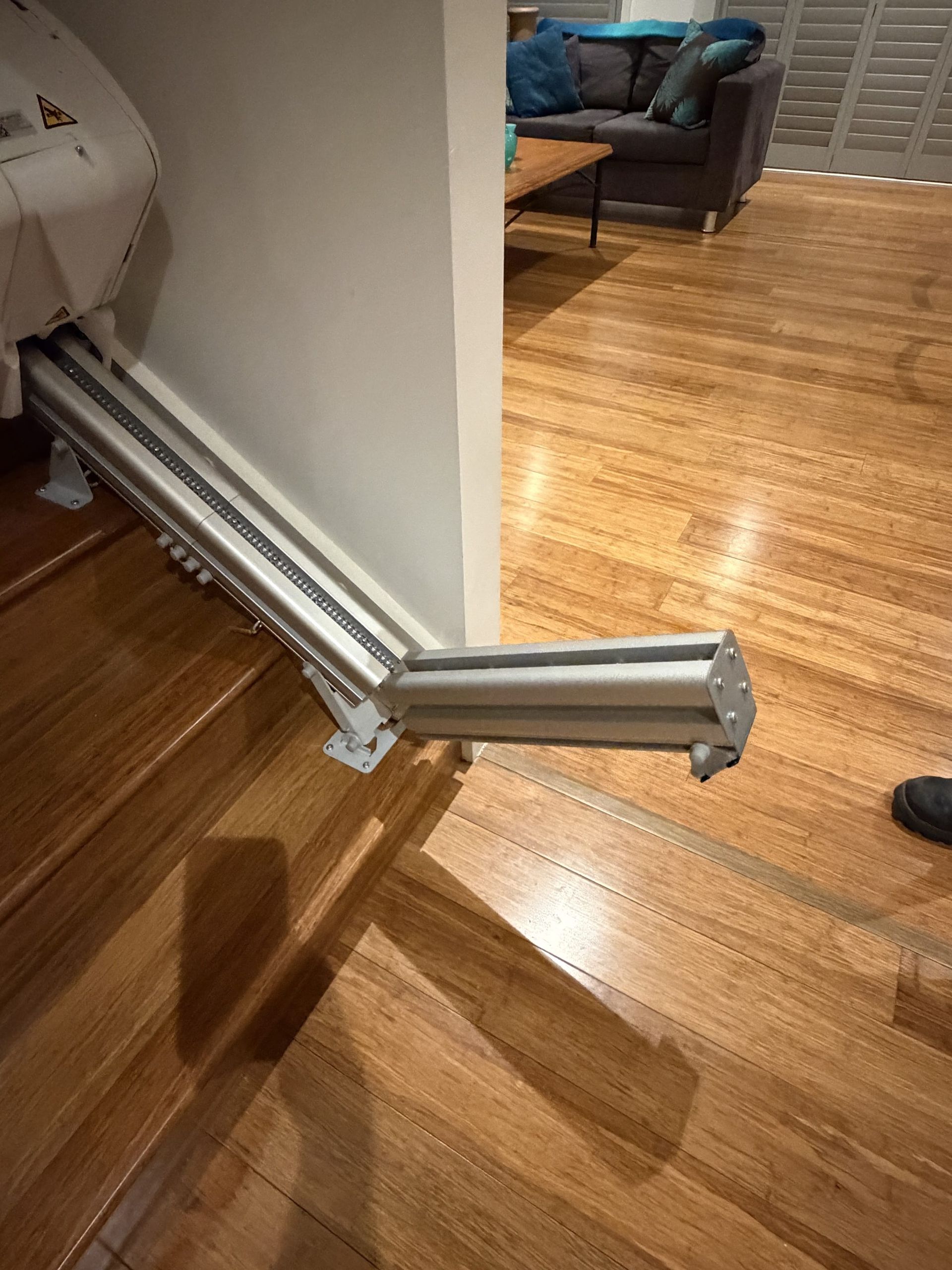 Folded metal exercise machine leaning against a wall on a hardwood floor in a living room.