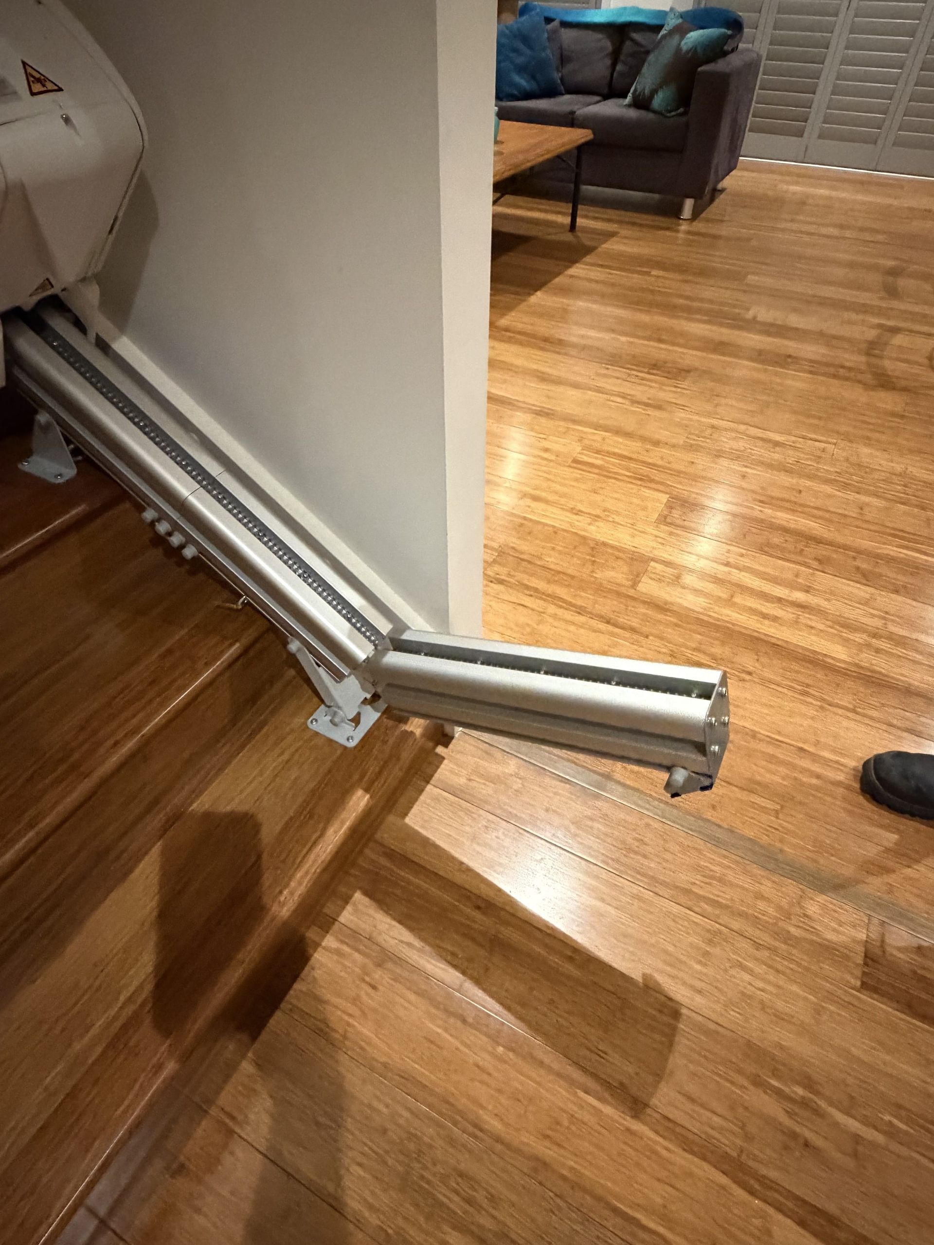 Opened silver retractable gate blocking a doorway in a hardwood-floored room
