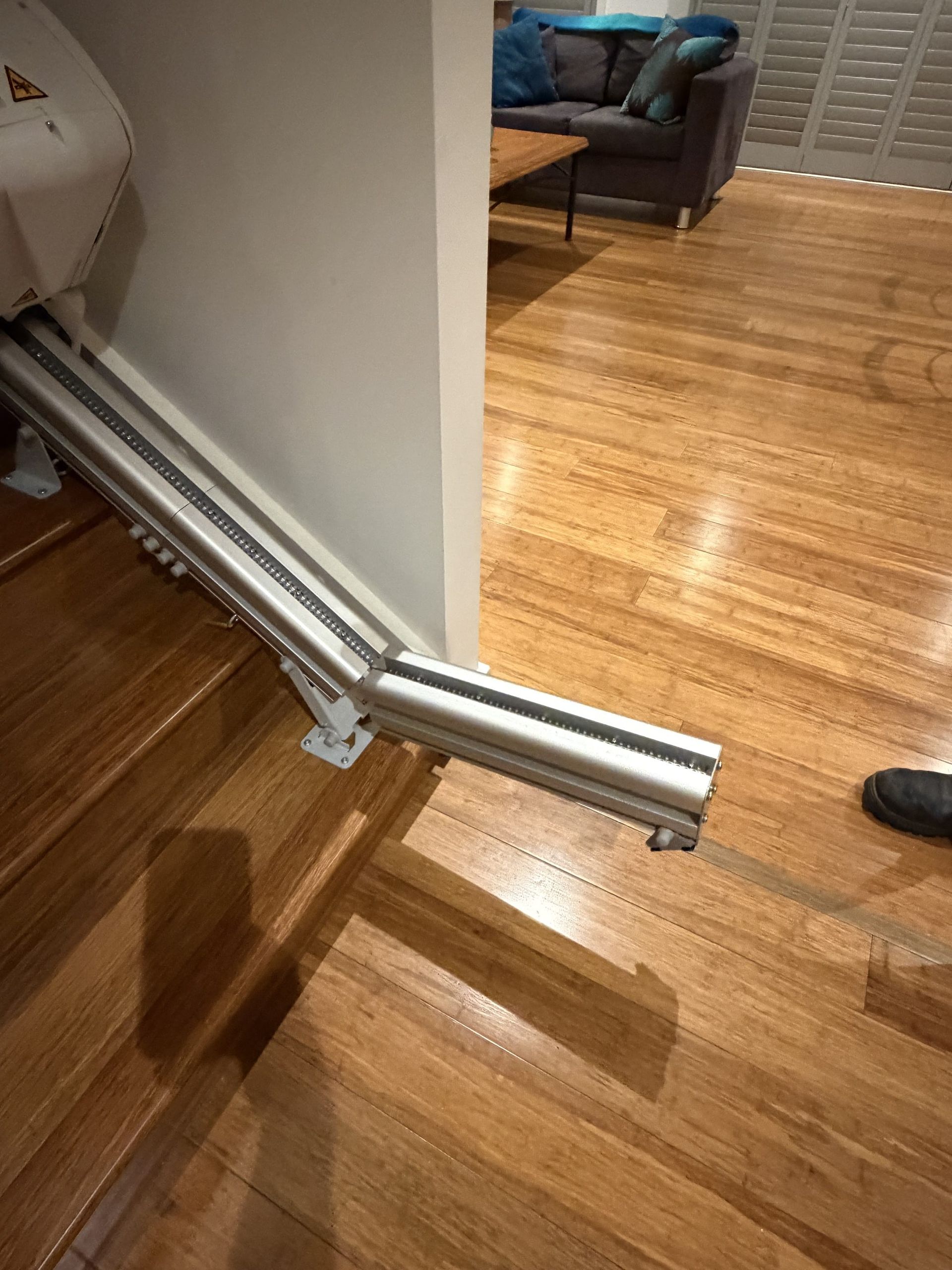 Broken metal rail on a hardwood floor beside a wall in a living room