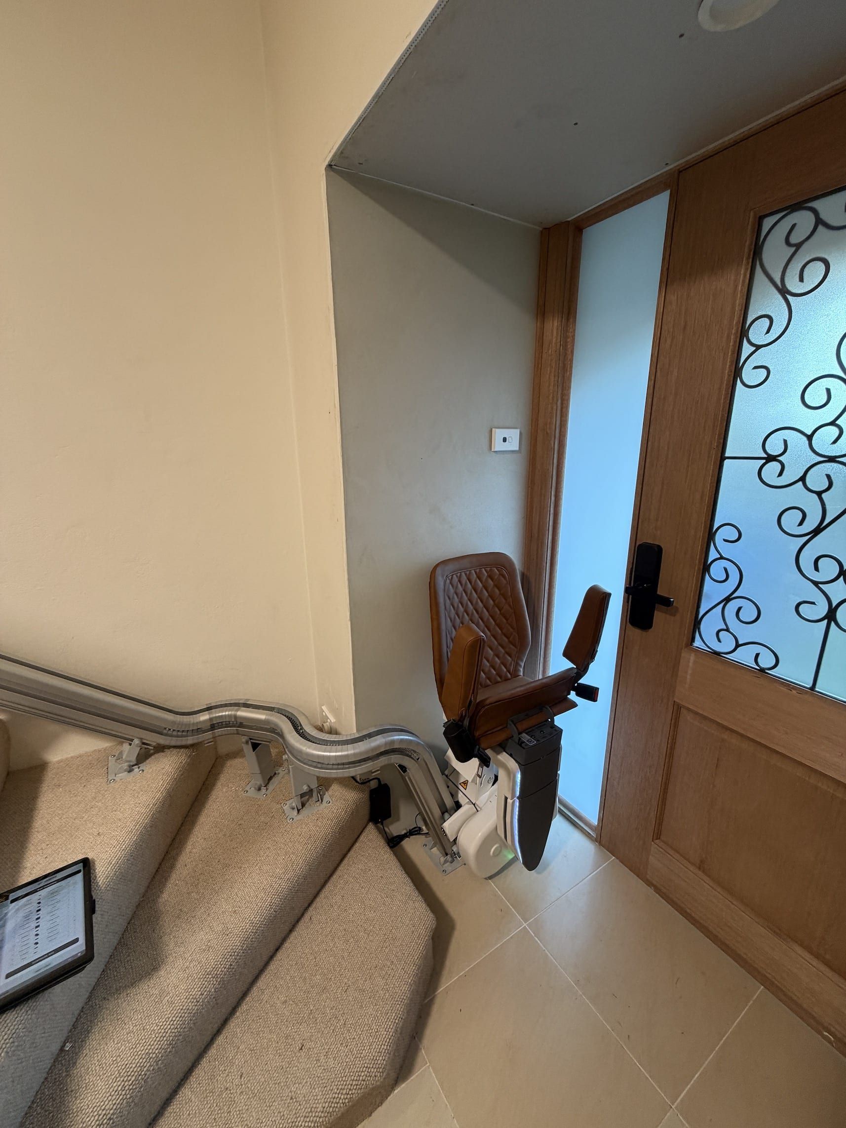 Indoor staircase beside a wooden front door, with a small chair near the entryway.