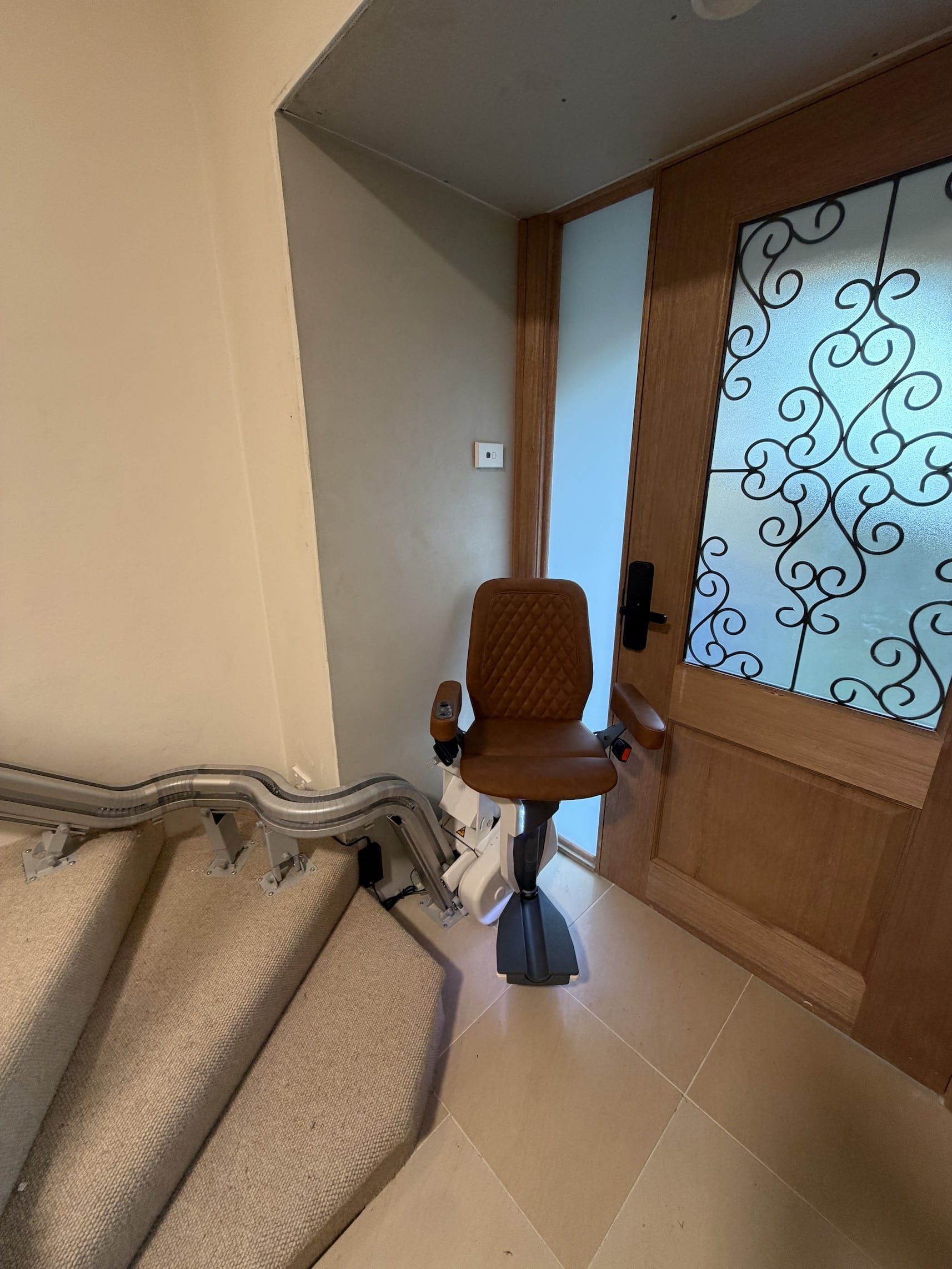 Small chair near a doorway beside folded rugs in a tiled entryway