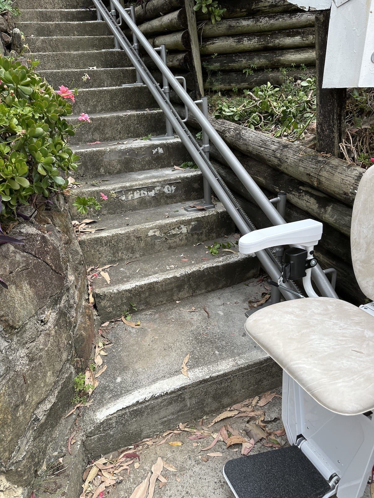 Steep outdoor concrete stairs with a metal rail lift installed alongside them.