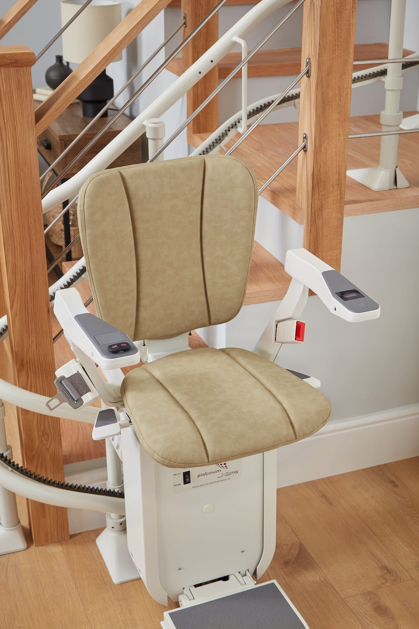 Beige stairlift chair beside wooden stairs in a home interior.