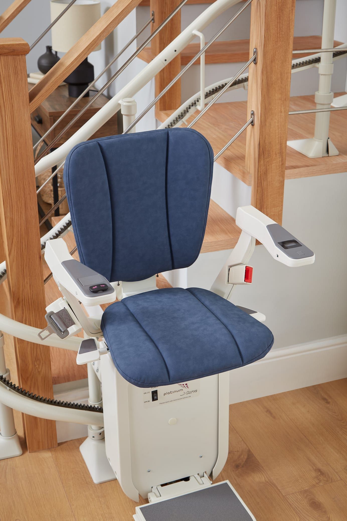 Blue stairlift chair mounted on a wooden staircase with white rails and a curved stair rail