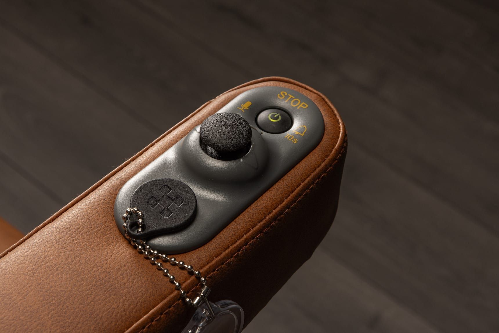 Brown leather case with a black remote control and a small yellow button on a dark background
