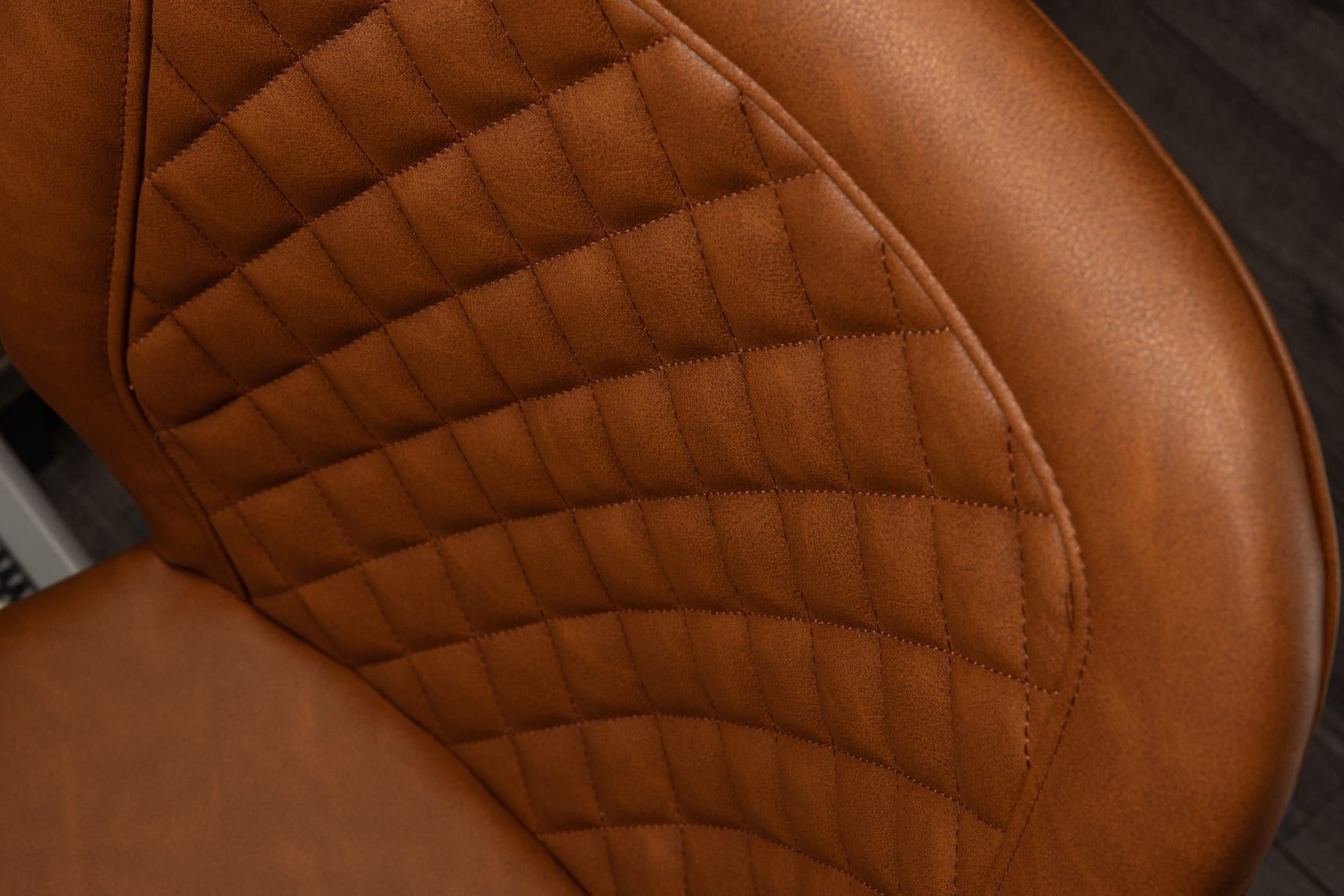 Close-up of a brown quilted leather car seat with stitched diamond pattern