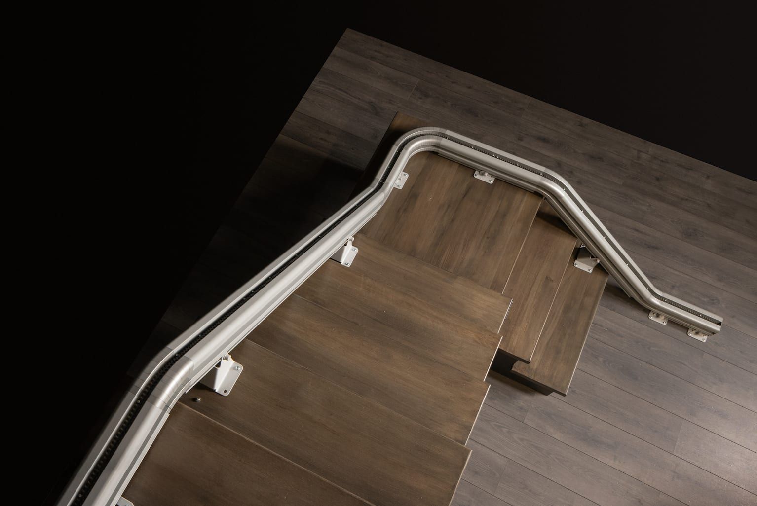 Wooden staircase railing components laid out on a floor, showing curved white handrails and brown steps.