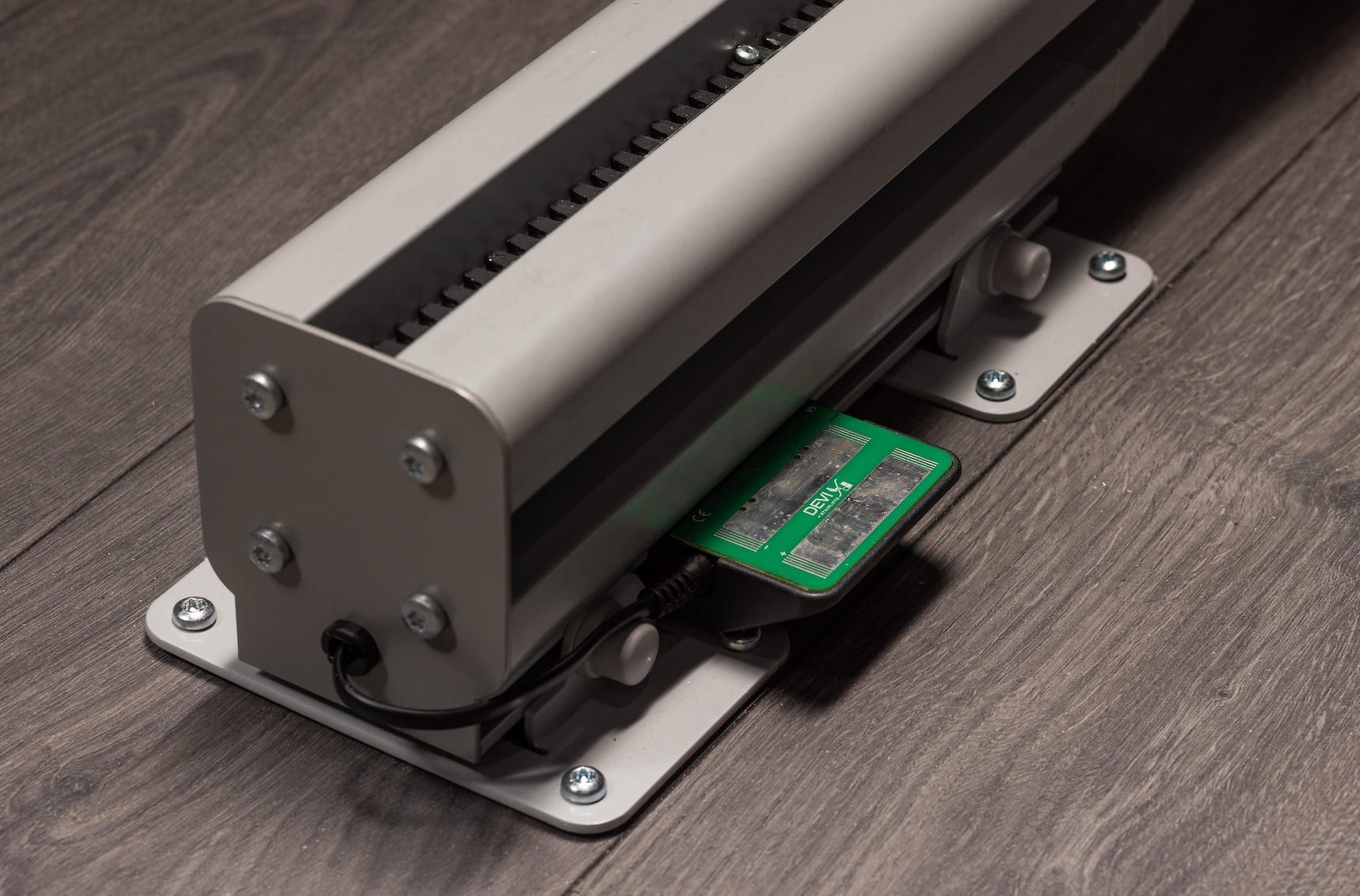 Small metal device with a green circuit board mounted on a wooden surface
