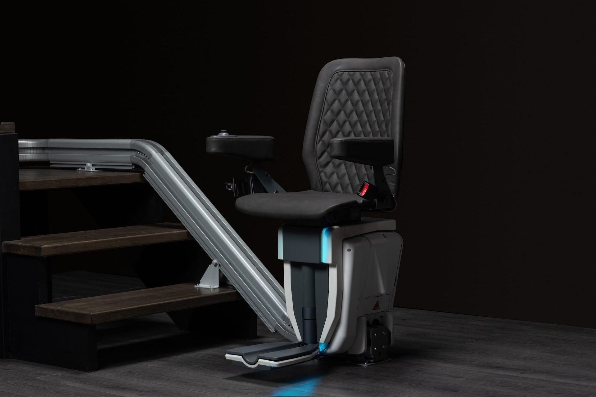 Modern stair lift chair with black seat and silver rail on stairs